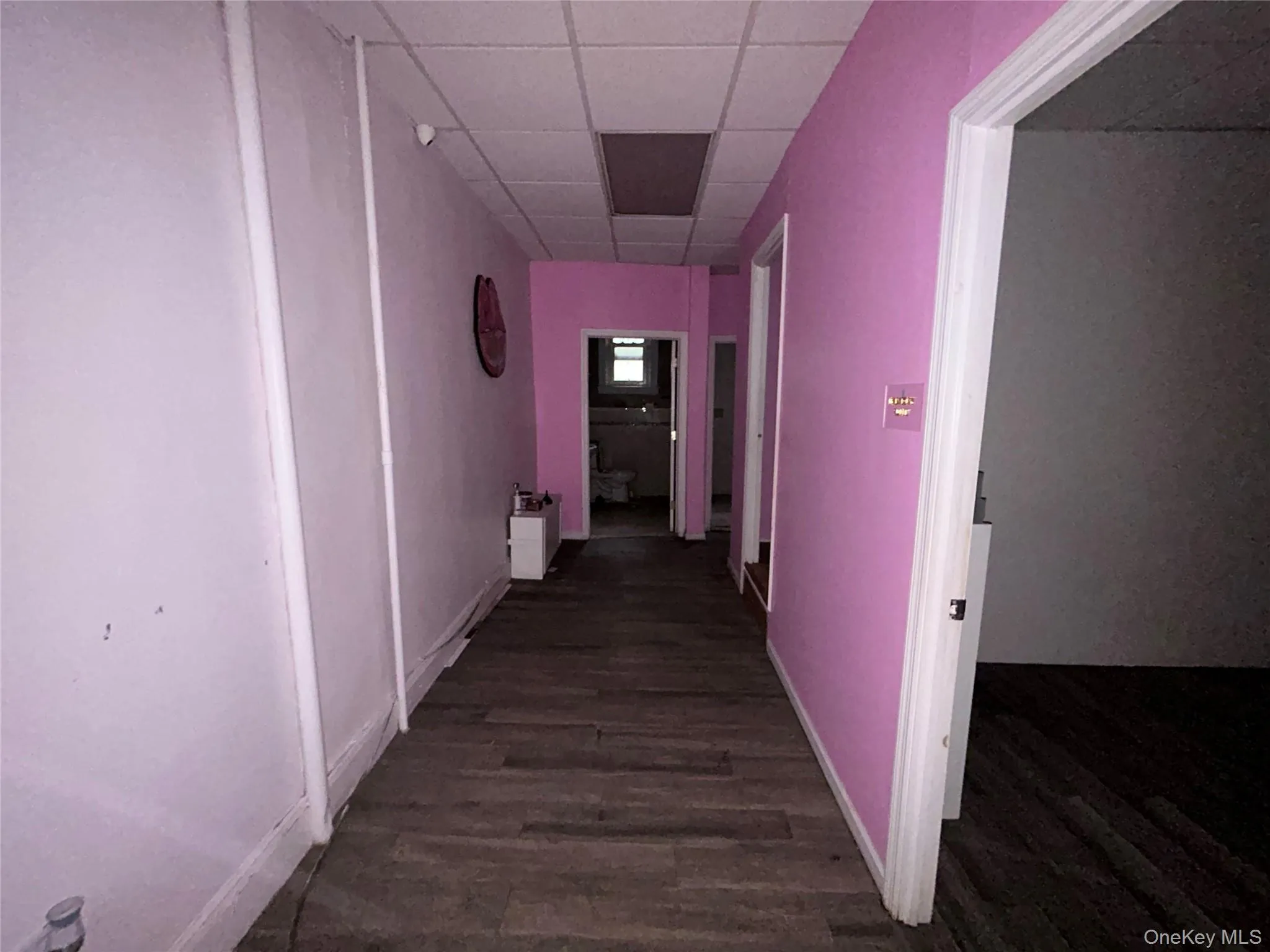 Hall featuring a paneled ceiling and dark wood-style floors Hall featuring a paneled ceiling and dark wood-style floors