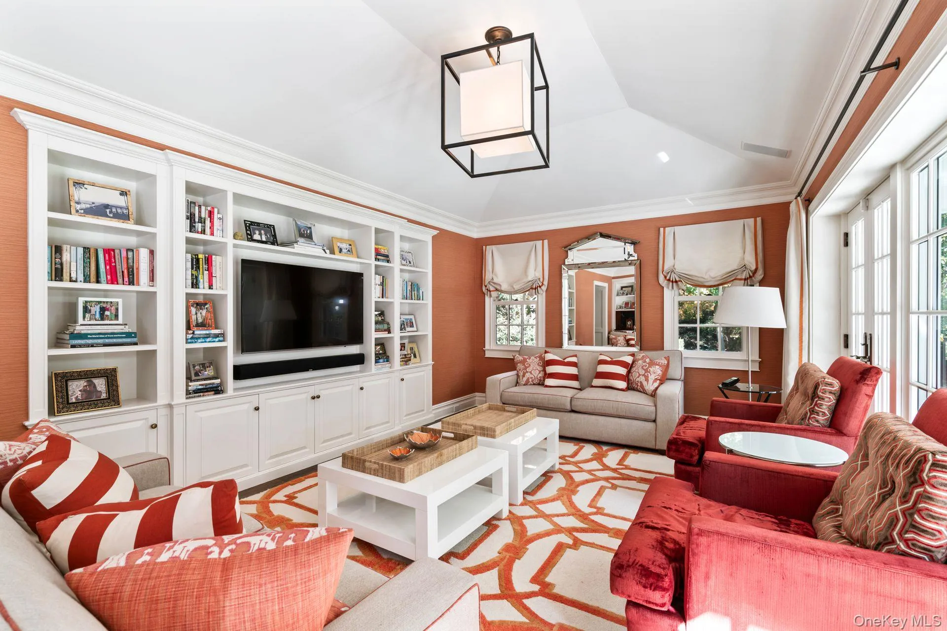 Living area featuring vaulted ceiling, built in shelves, visible vents, and ornamental molding Living area featuring vaulted ceiling, built in shelves, visible vents, and ornamental molding