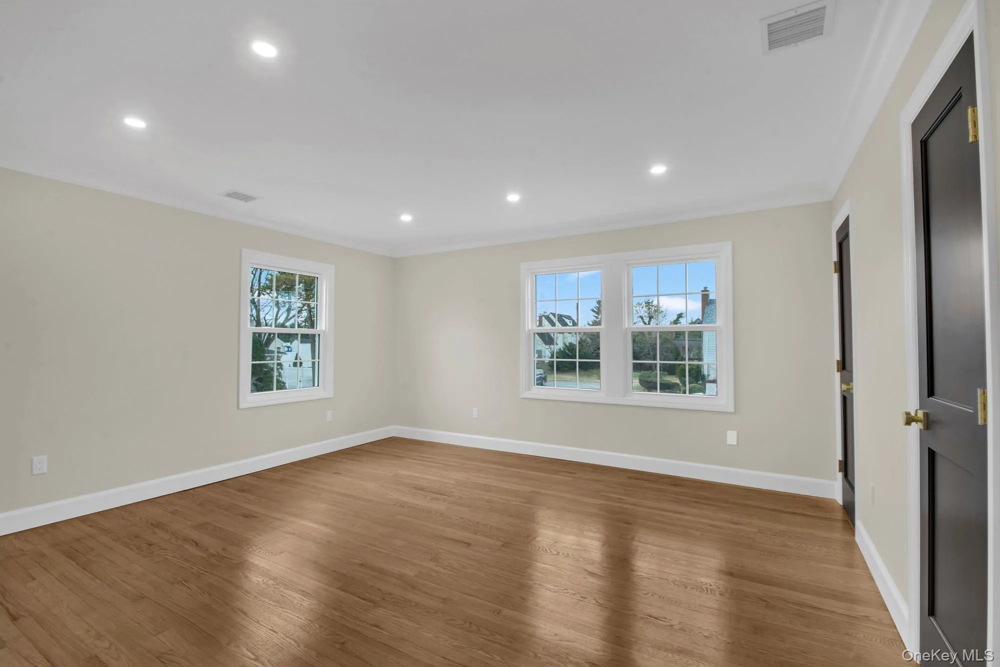 Corner larger bedroom with wood finished floors, recessed lighting, and ornamental molding Corner larger bedroom with wood finished floors, recessed lighting, and ornamental molding