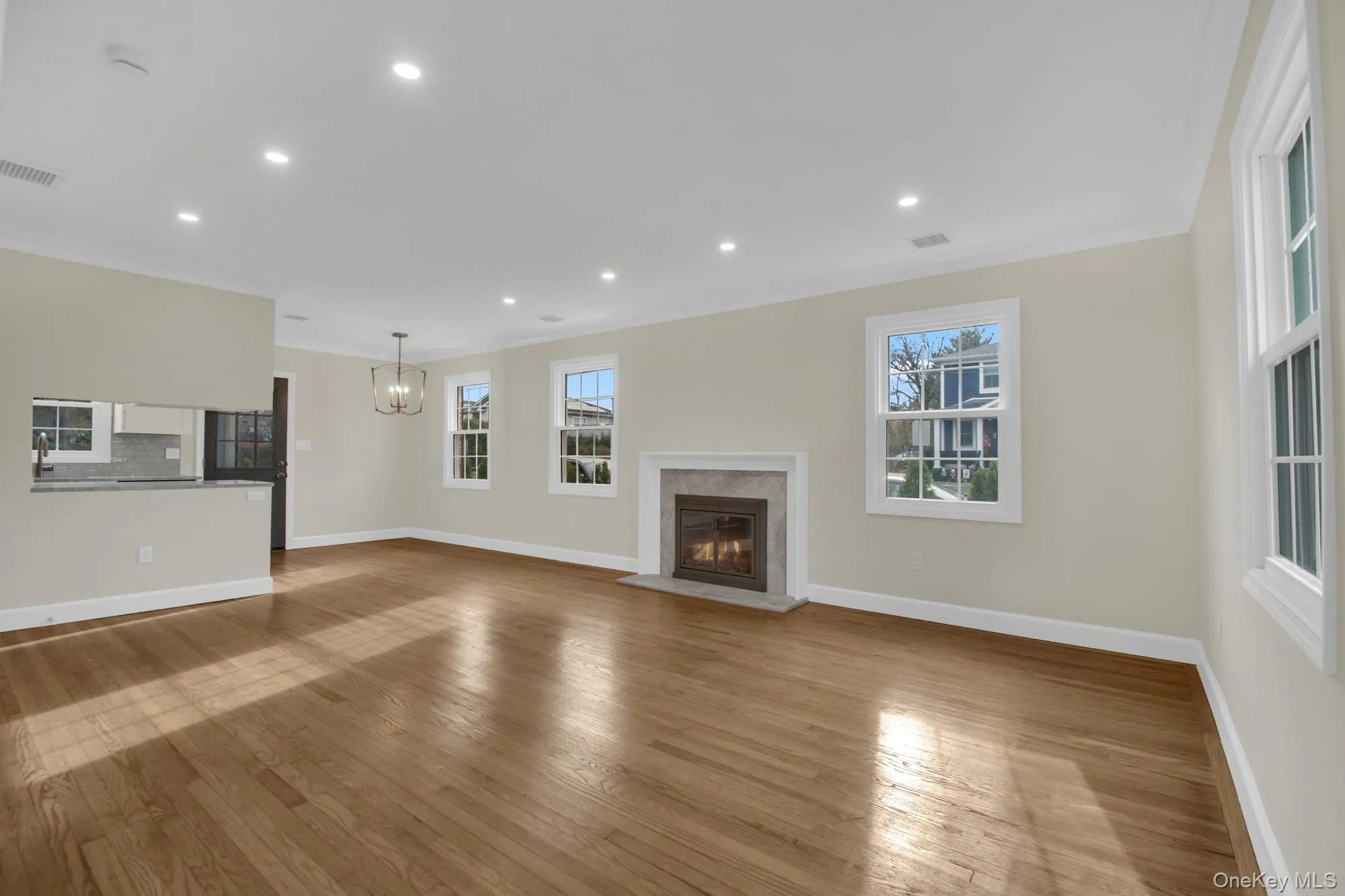 Open/ Bright living room with recessed lighting, crown molding, a fireplace, light wood finished floors, and a chandelier Open/ Bright living room with recessed lighting, crown molding, a fireplace, light wood finished floors, and a chandelier