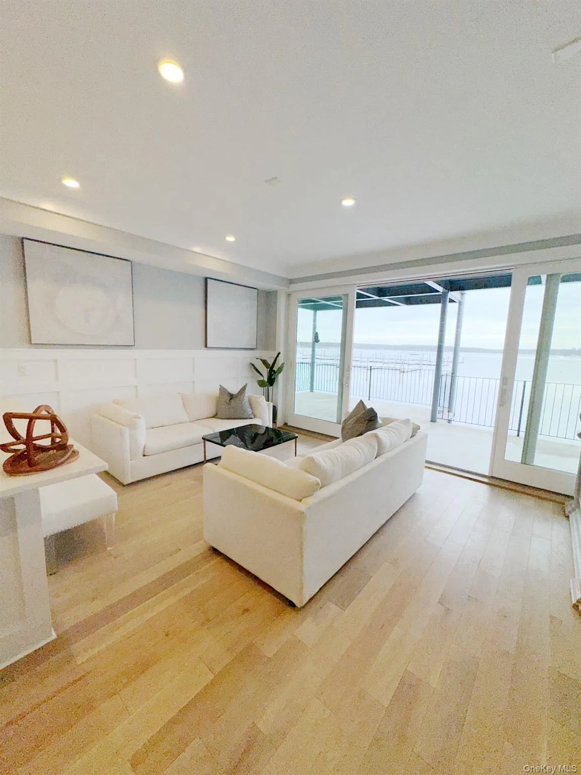 Living area with a decorative wall, light wood-type flooring, a water view, and recessed lighting Living area with a decorative wall, light wood-type flooring, a water view, and recessed lighting
