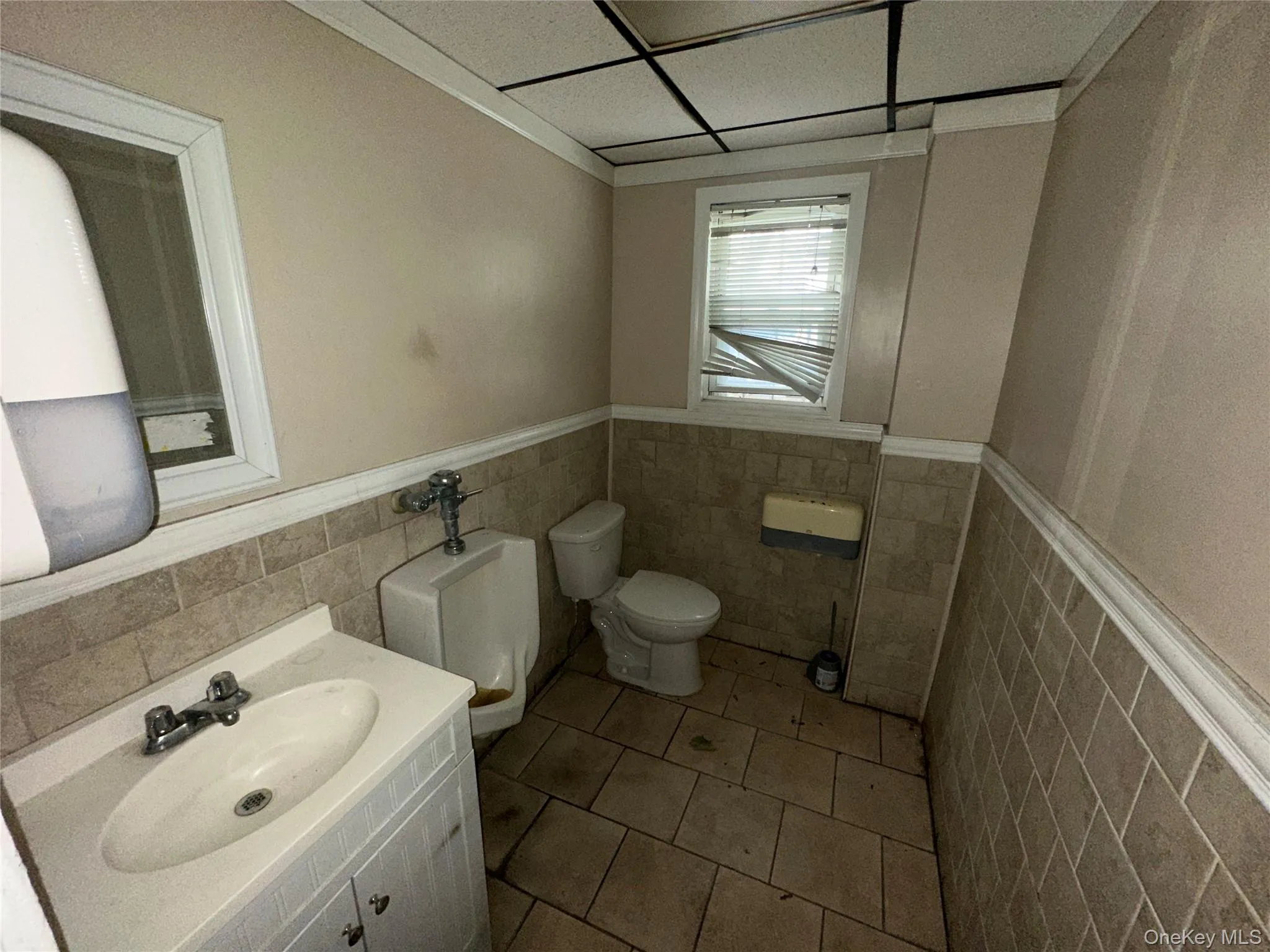 Bathroom with a wainscoted wall, vanity, tile patterned floors, and tile walls Bathroom with a wainscoted wall, vanity, tile patterned floors, and tile walls
