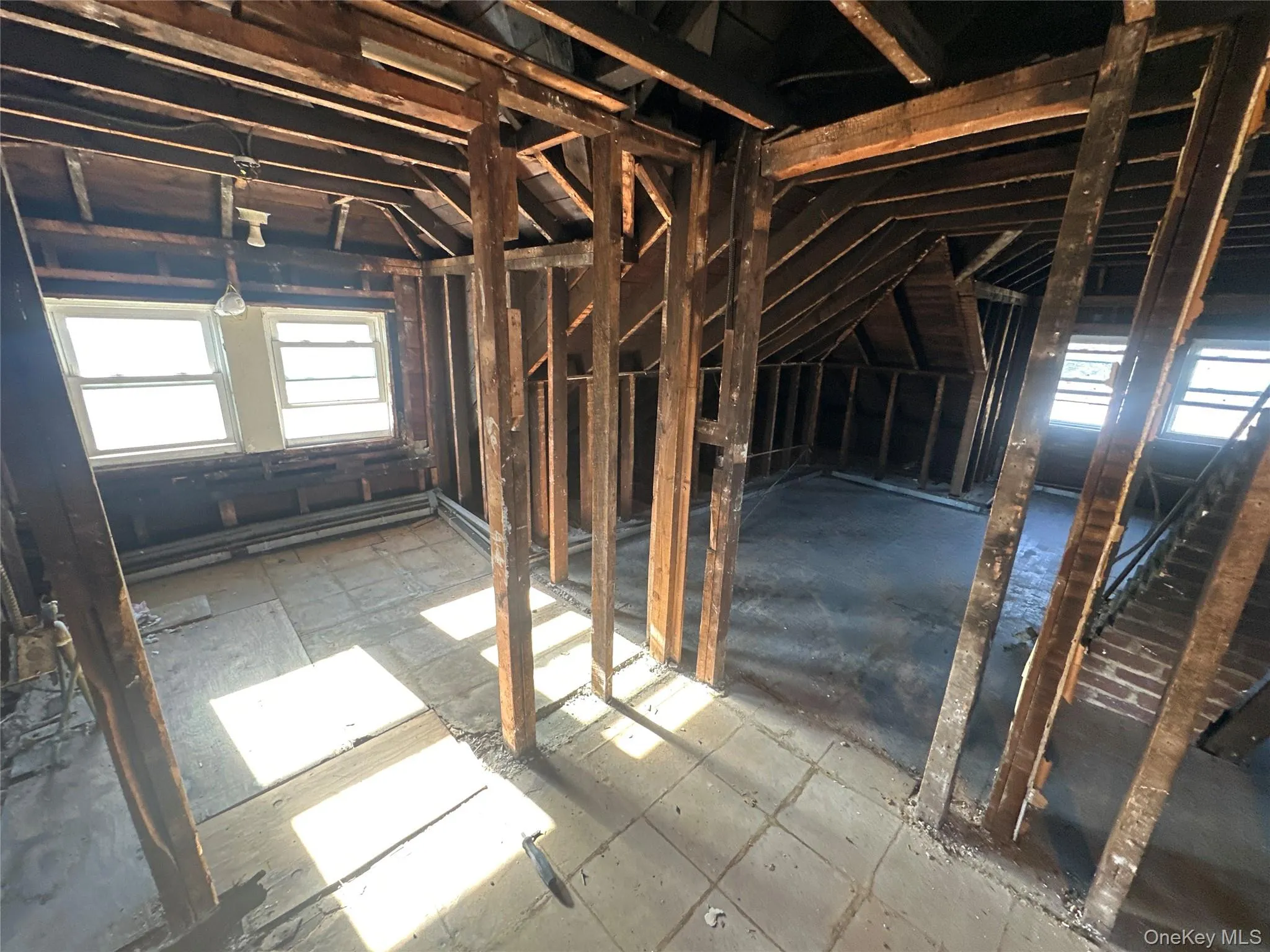 Unfinished attic featuring plenty of natural light and a baseboard radiator Unfinished attic featuring plenty of natural light and a baseboard radiator