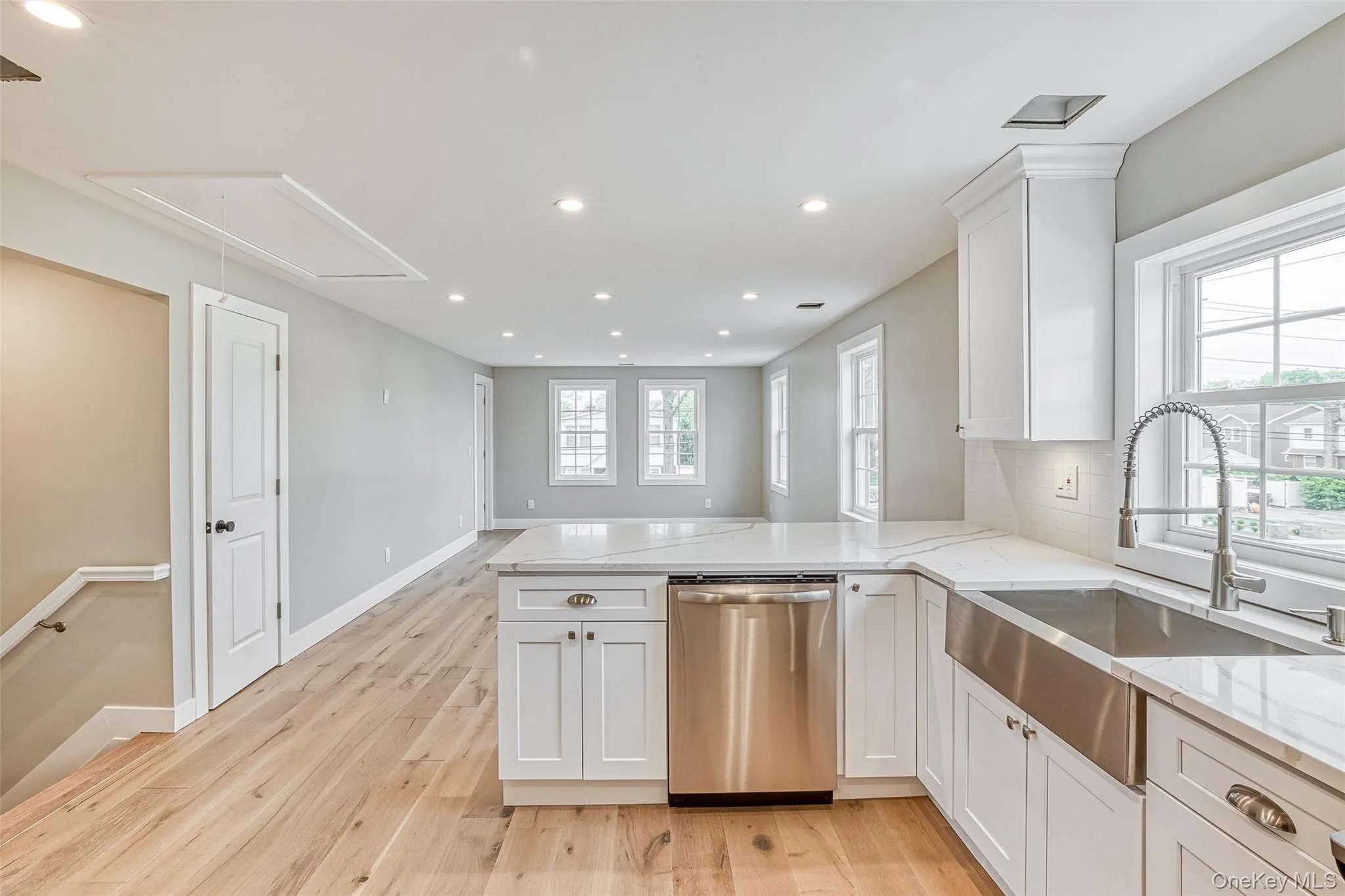 Kitchen featuring recessed lighting, dishwasher, white cabinetry, light stone counters, and a peninsula Kitchen featuring recessed lighting, dishwasher, white cabinetry, light stone counters, and a peninsula