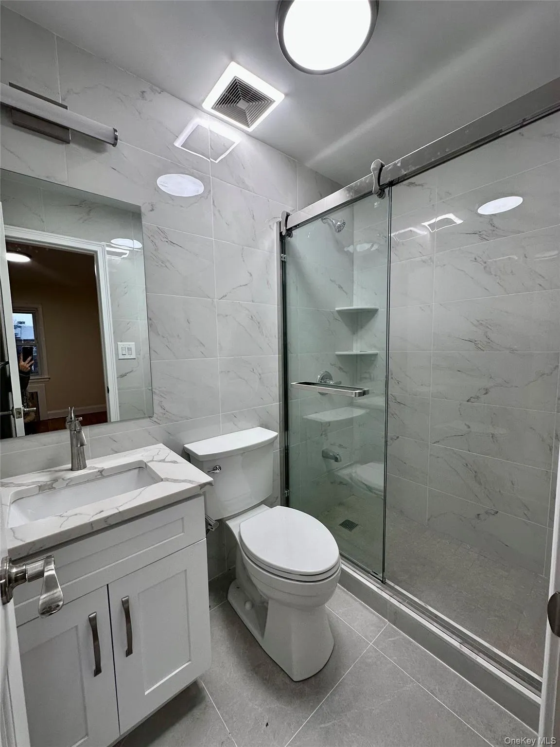 Bathroom with tile walls, vanity, and a marble finish shower Bathroom with tile walls, vanity, and a marble finish shower