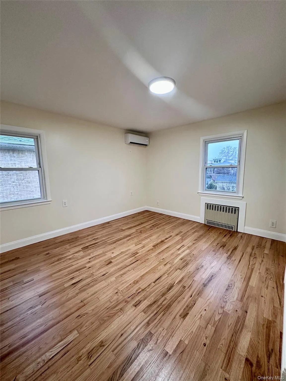Unfurnished room featuring light wood finished floors and radiator heating unit Unfurnished room featuring light wood finished floors and radiator heating unit