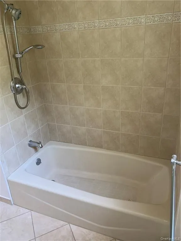 Bathroom featuring tile patterned floors and washtub / shower combination Bathroom featuring tile patterned floors and washtub / shower combination