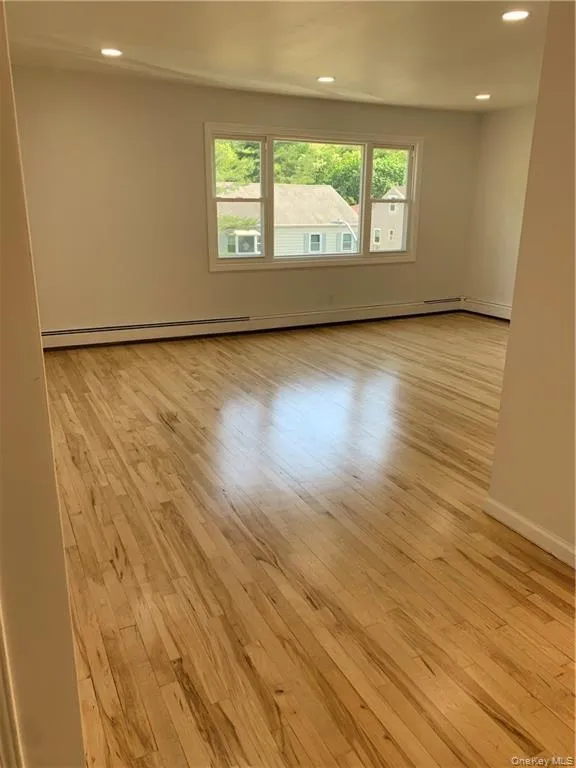 Unfurnished room featuring light wood-style floors, recessed lighting, and a baseboard heating unit Unfurnished room featuring light wood-style floors, recessed lighting, and a baseboard heating unit