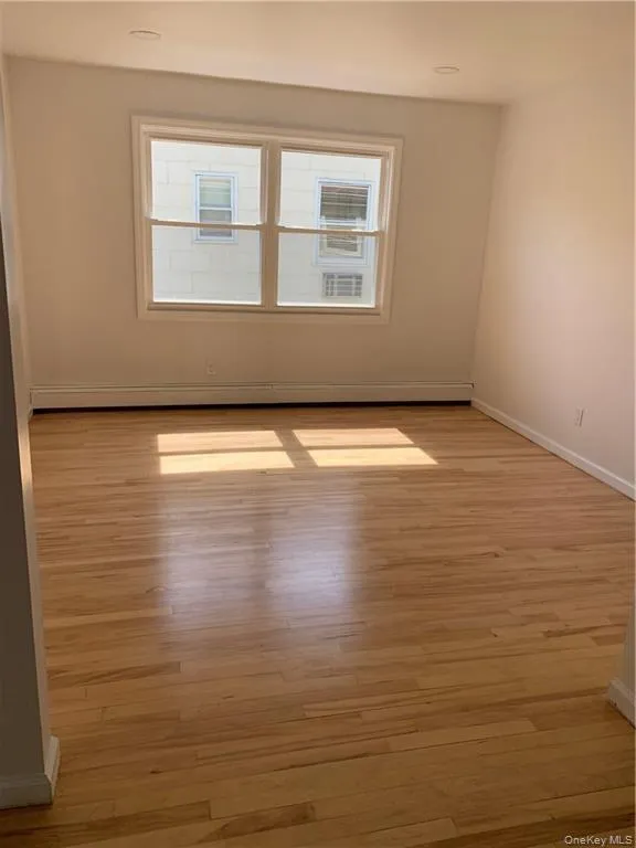 Spare room with a baseboard radiator and light wood-style flooring Spare room with a baseboard radiator and light wood-style flooring