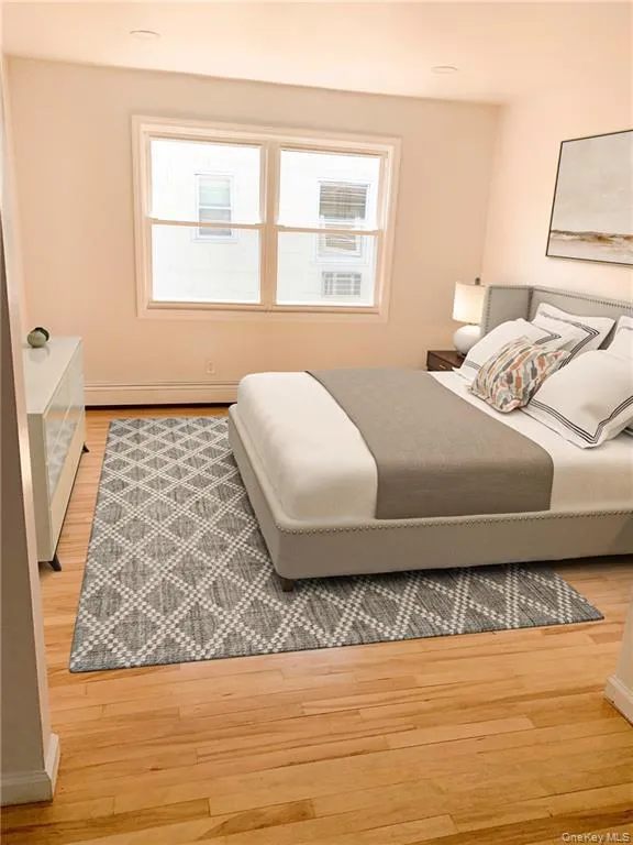 Bedroom with light wood-style floors and a baseboard heating unit Bedroom with light wood-style floors and a baseboard heating unit
