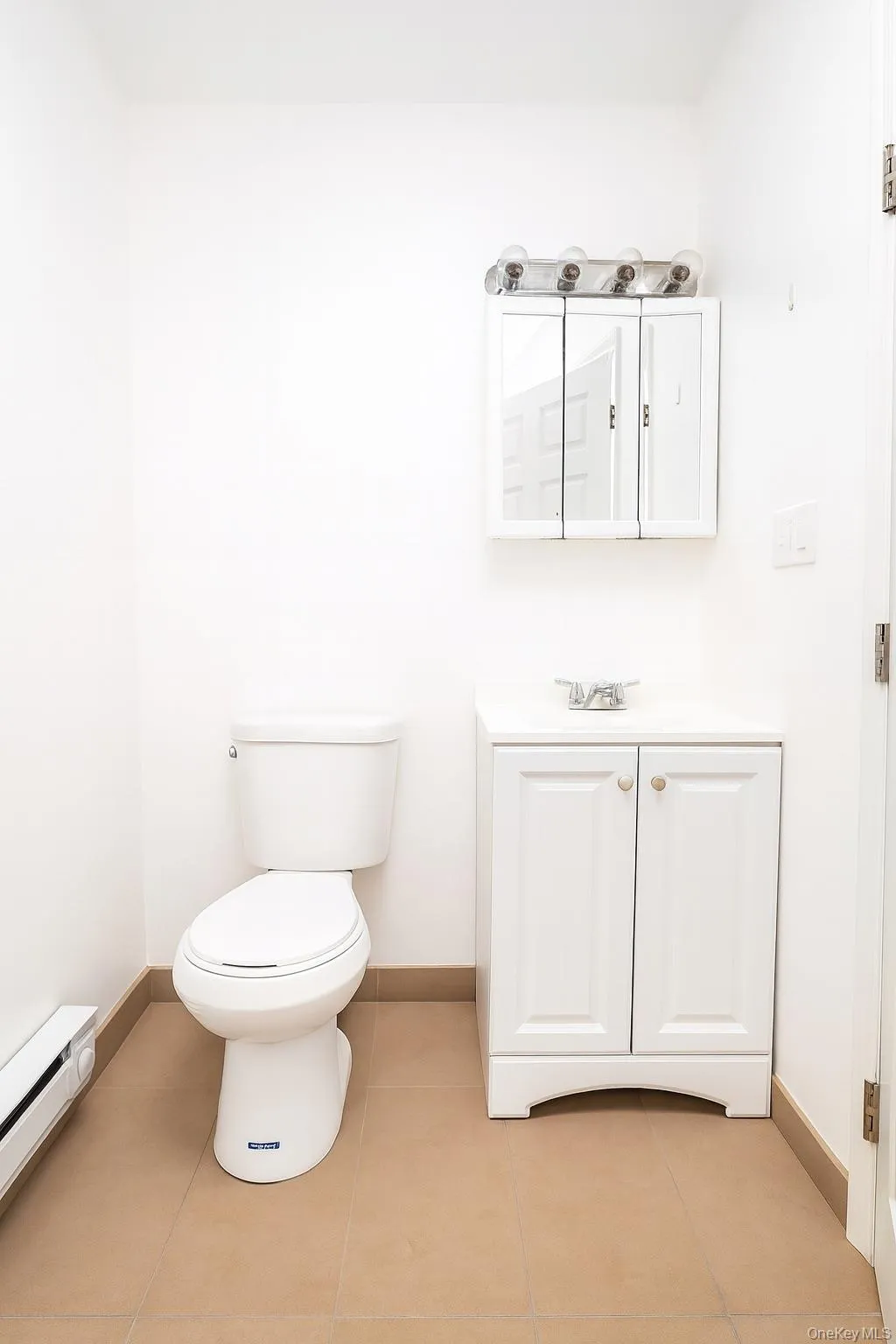Half bathroom featuring vanity, a baseboard heating unit, and light tile patterned flooring Half bathroom featuring vanity, a baseboard heating unit, and light tile patterned flooring