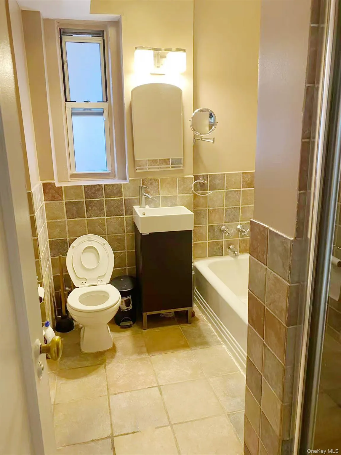 Full bathroom with tile walls, a bath, vanity, wainscoting, and a stall shower Full bathroom with tile walls, a bath, vanity, wainscoting, and a stall shower