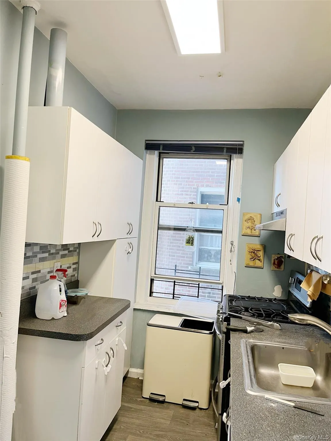 Kitchen featuring white cabinets, dark countertops, dark wood-style floors, gas stove, and under cabinet range hood Kitchen featuring white cabinets, dark countertops, dark wood-style floors, gas stove, and under cabinet range hood