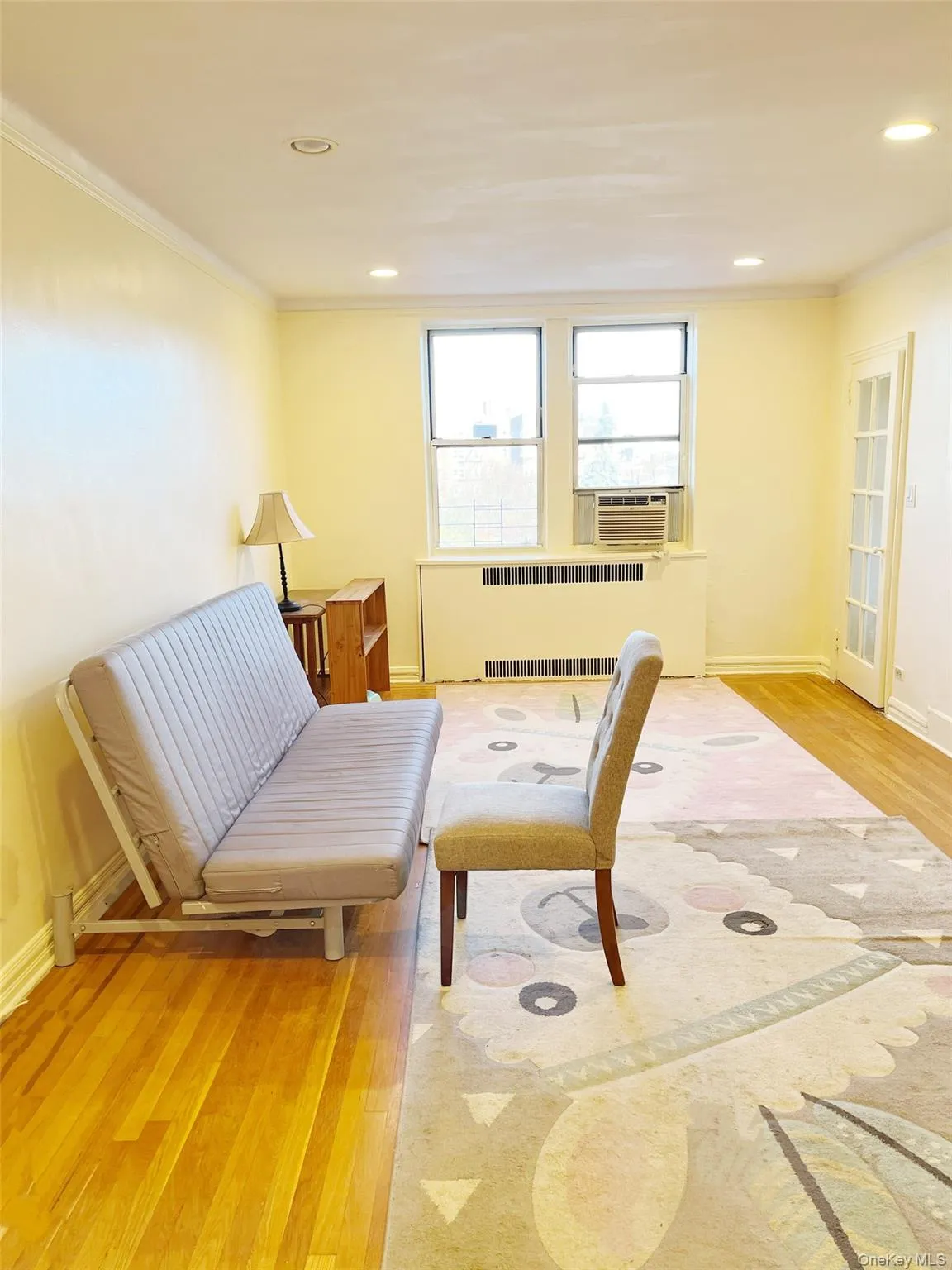 Sitting room with light wood-style flooring, radiator heating unit, crown molding, recessed lighting, and cooling unit Sitting room with light wood-style flooring, radiator heating unit, crown molding, recessed lighting, and cooling unit
