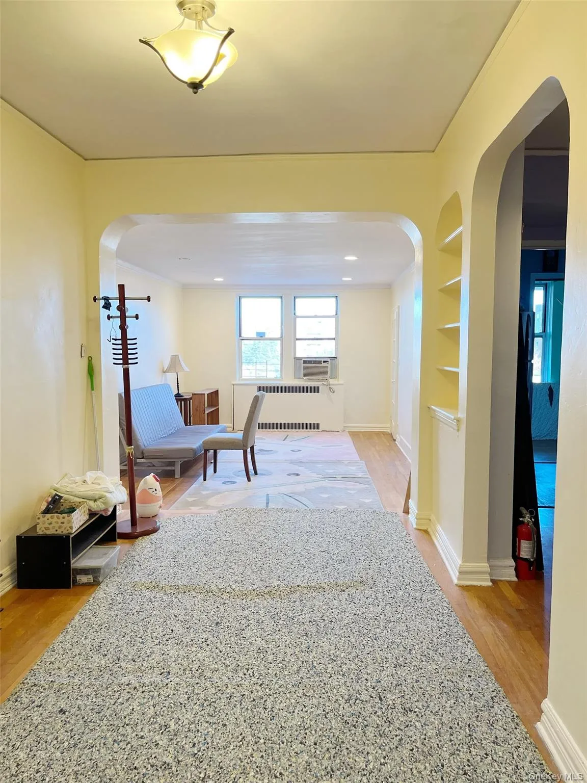 Hallway featuring arched walkways, built in features, and light wood-style floors Hallway featuring arched walkways, built in features, and light wood-style floors