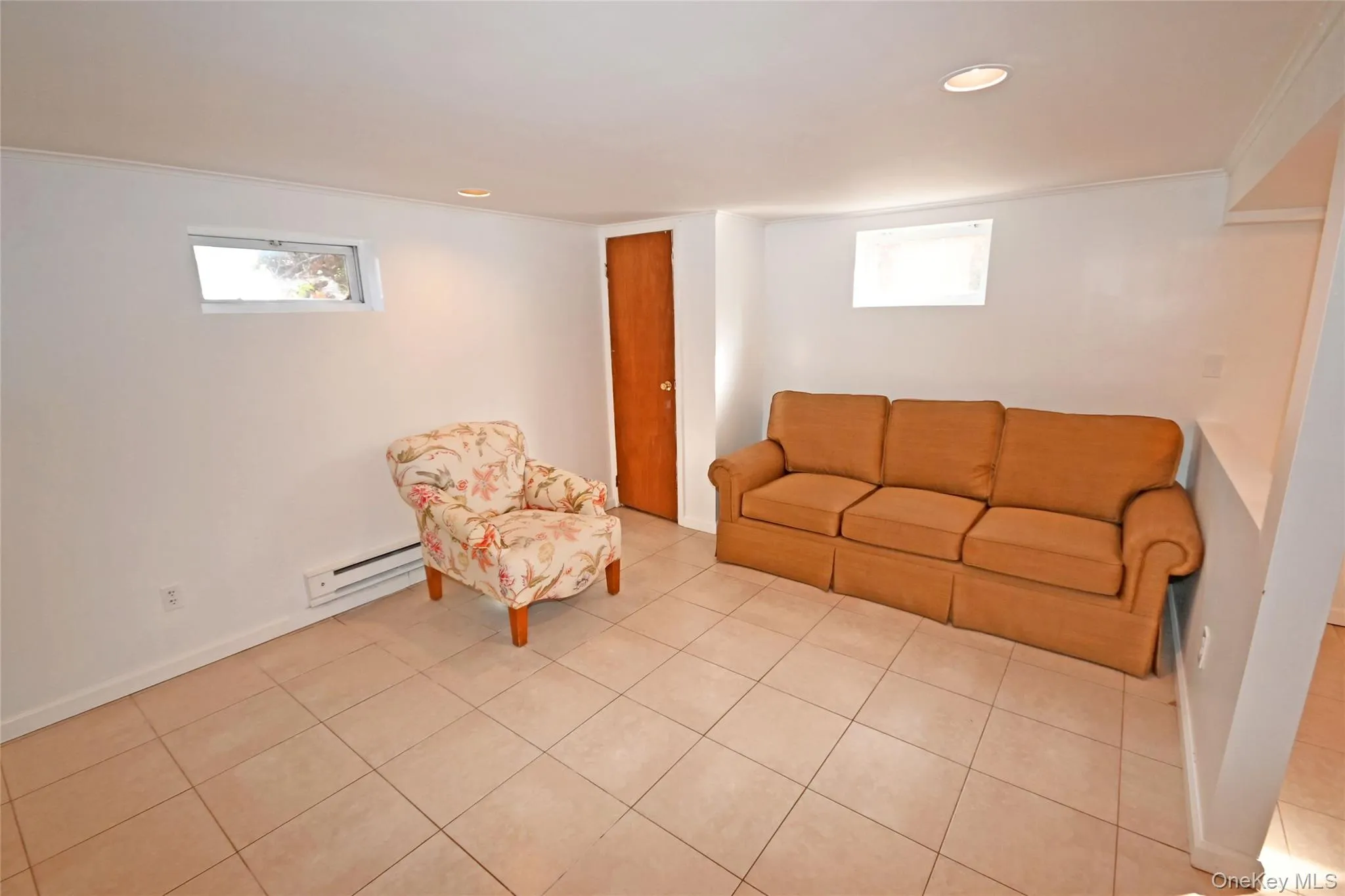 Living area with a baseboard radiator, recessed lighting, tile patterned flooring, and crown molding Living area with a baseboard radiator, recessed lighting, tile patterned flooring, and crown molding