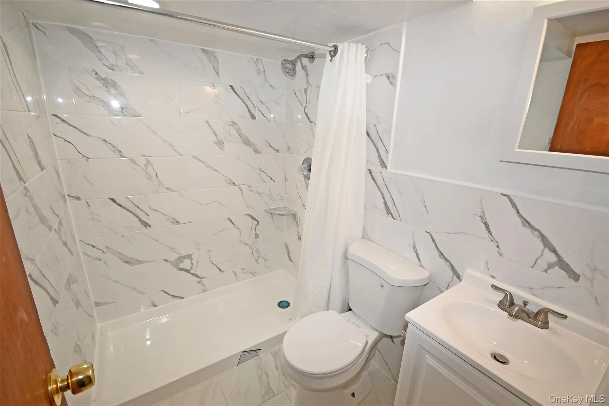 Full bath with tile walls, vanity, a shower stall, and marble look tiles Full bath with tile walls, vanity, a shower stall, and marble look tiles