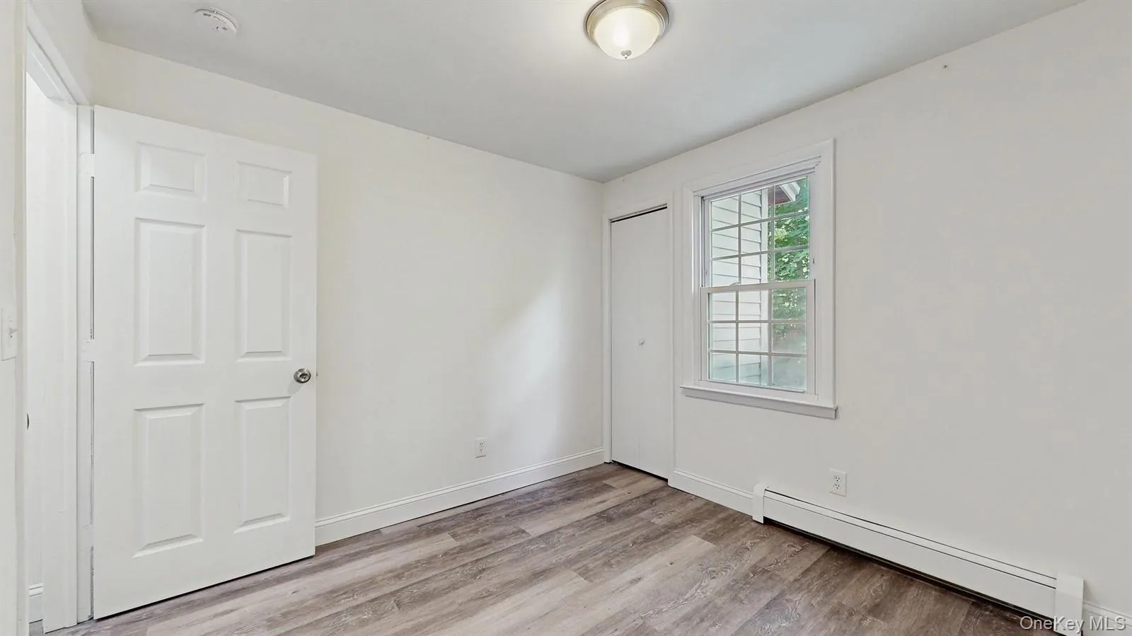 Empty room with a baseboard radiator and light wood-style flooring Empty room with a baseboard radiator and light wood-style flooring