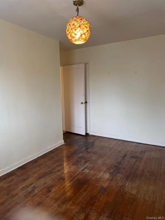Unfurnished room with baseboards and dark wood-style floors Unfurnished room with baseboards and dark wood-style floors
