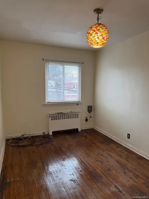 Empty room with radiator and dark wood finished floors Empty room with radiator and dark wood finished floors