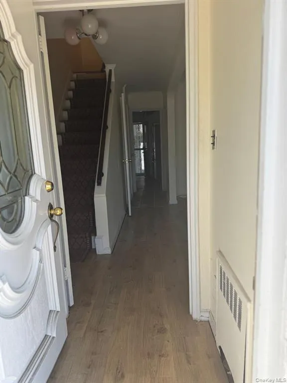 Hallway featuring light wood-style floors, stairway, and radiator heating unit Hallway featuring light wood-style floors, stairway, and radiator heating unit