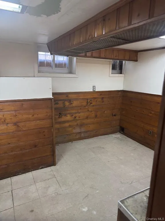 Below grade area with light floors, wood walls, and wainscoting Below grade area with light floors, wood walls, and wainscoting