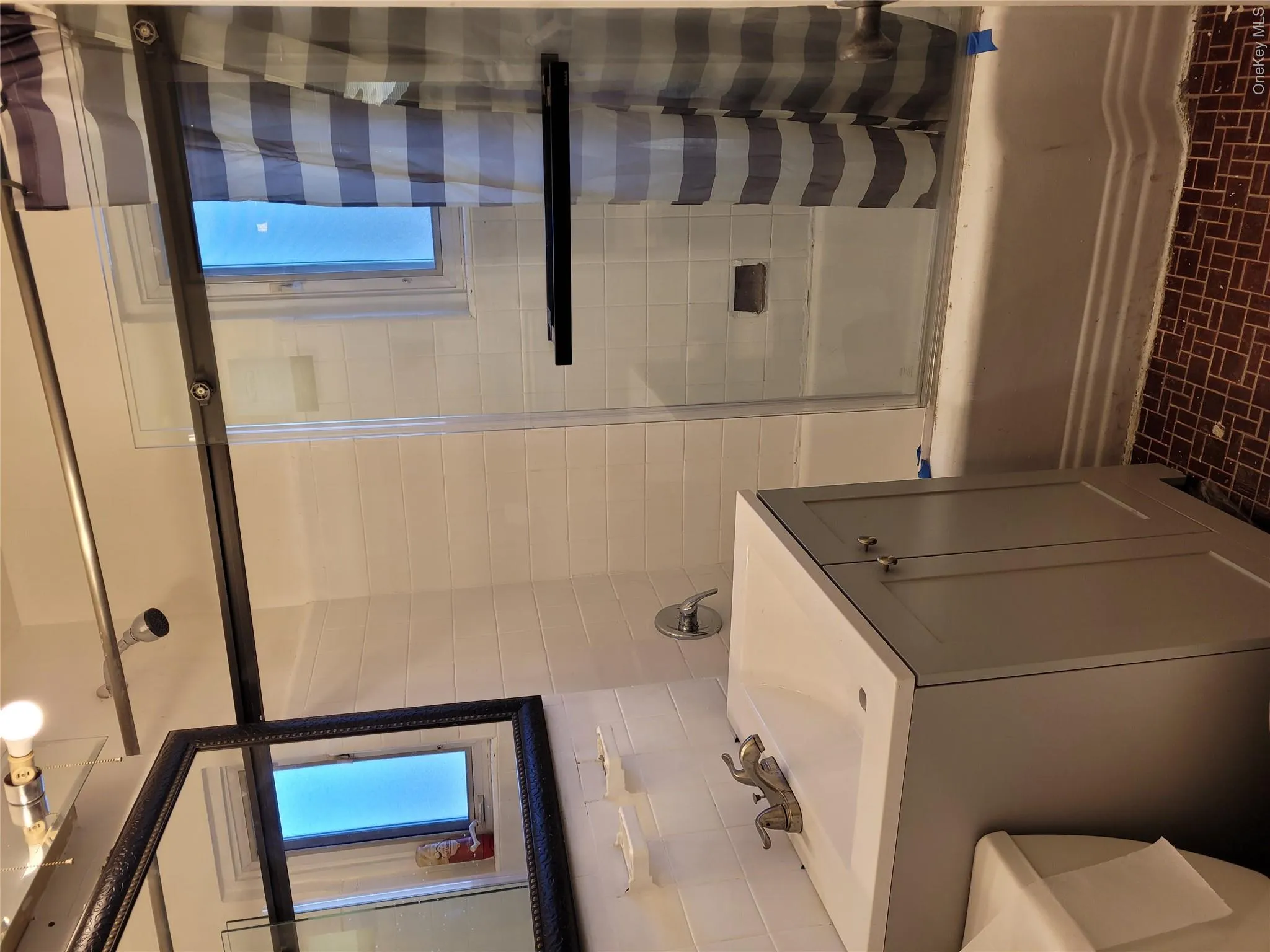 Full bath featuring combined bath / shower with glass door, vanity, tasteful backsplash, and tile walls Full bath featuring combined bath / shower with glass door, vanity, tasteful backsplash, and tile walls