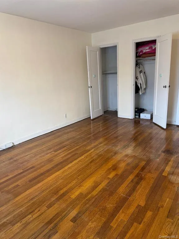 Unfurnished bedroom featuring two closets and dark wood-style flooring Unfurnished bedroom featuring two closets and dark wood-style flooring