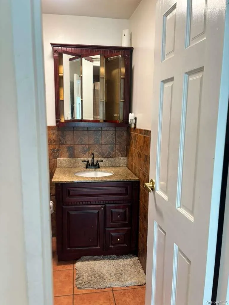 Half bathroom with vanity, tasteful backsplash, and light tile patterned floors Half bathroom with vanity, tasteful backsplash, and light tile patterned floors