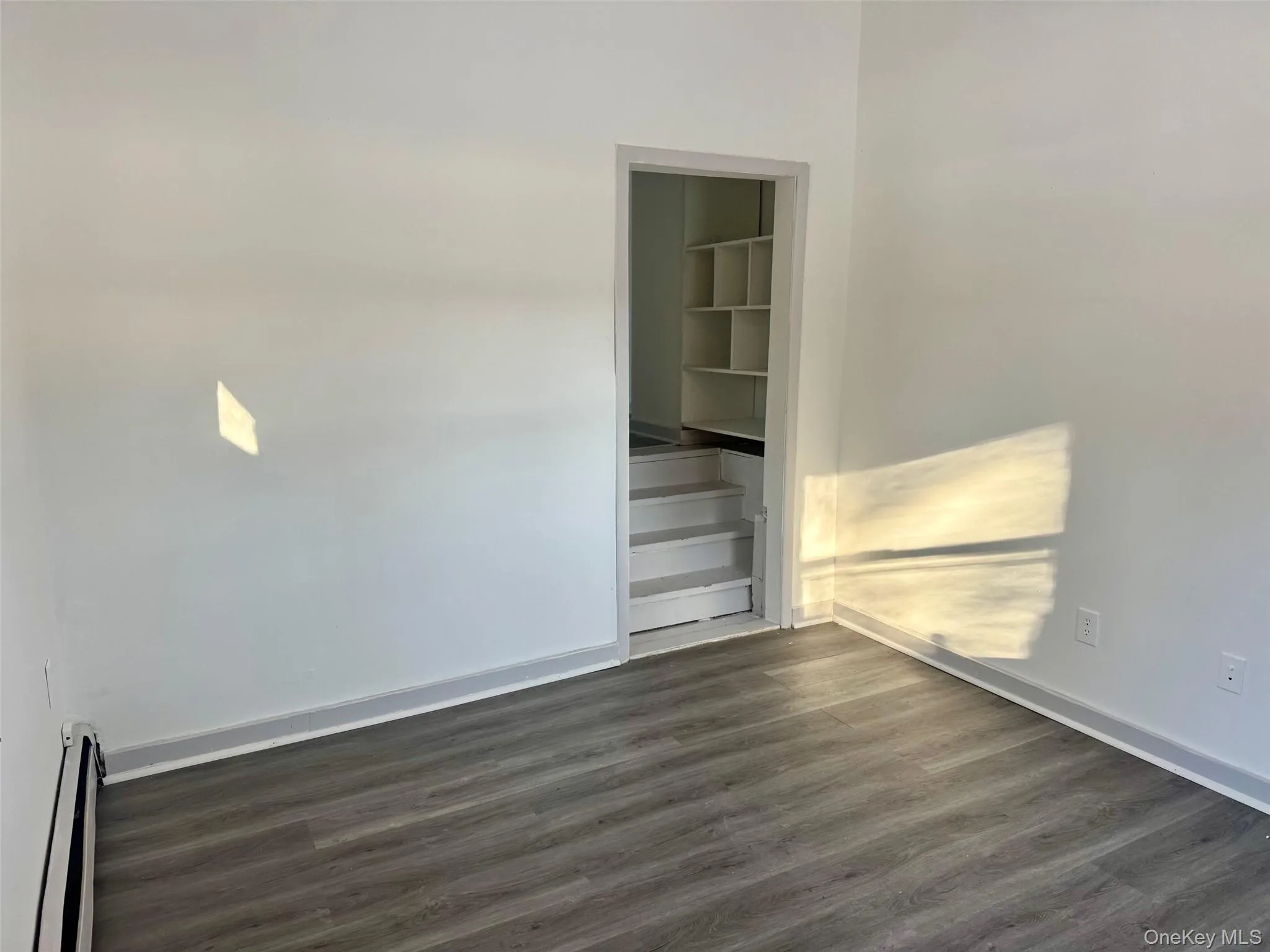 Spare room featuring dark wood-style floors and a baseboard heating unit Spare room featuring dark wood-style floors and a baseboard heating unit