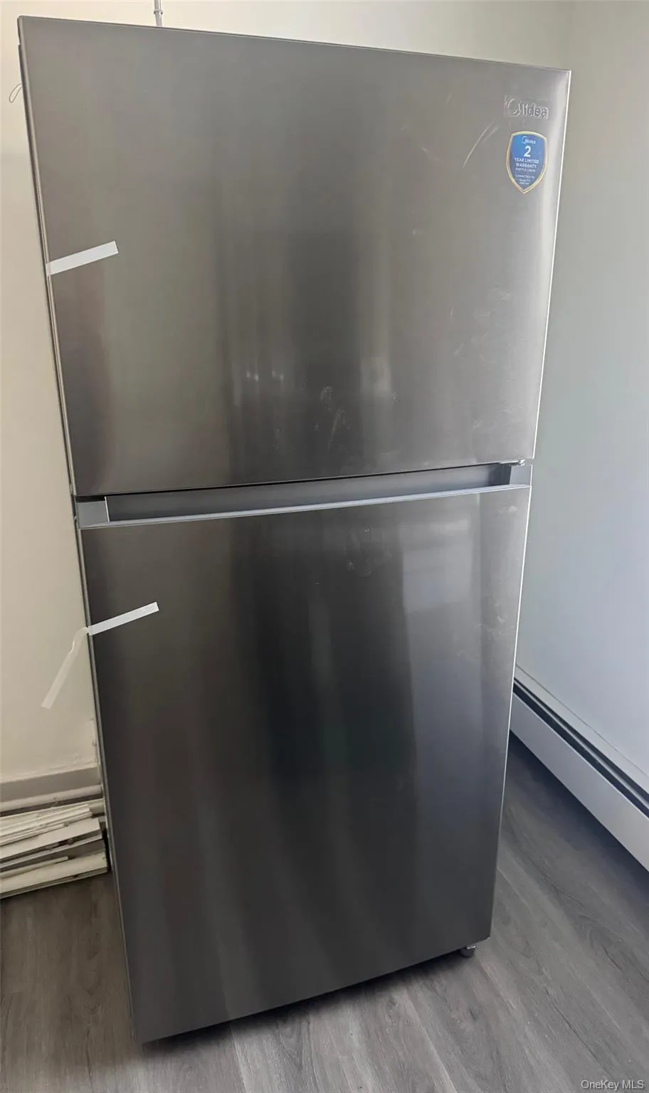 Kitchen view of freestanding refrigerator, baseboard heating, and light wood finished floors Kitchen view of freestanding refrigerator, baseboard heating, and light wood finished floors