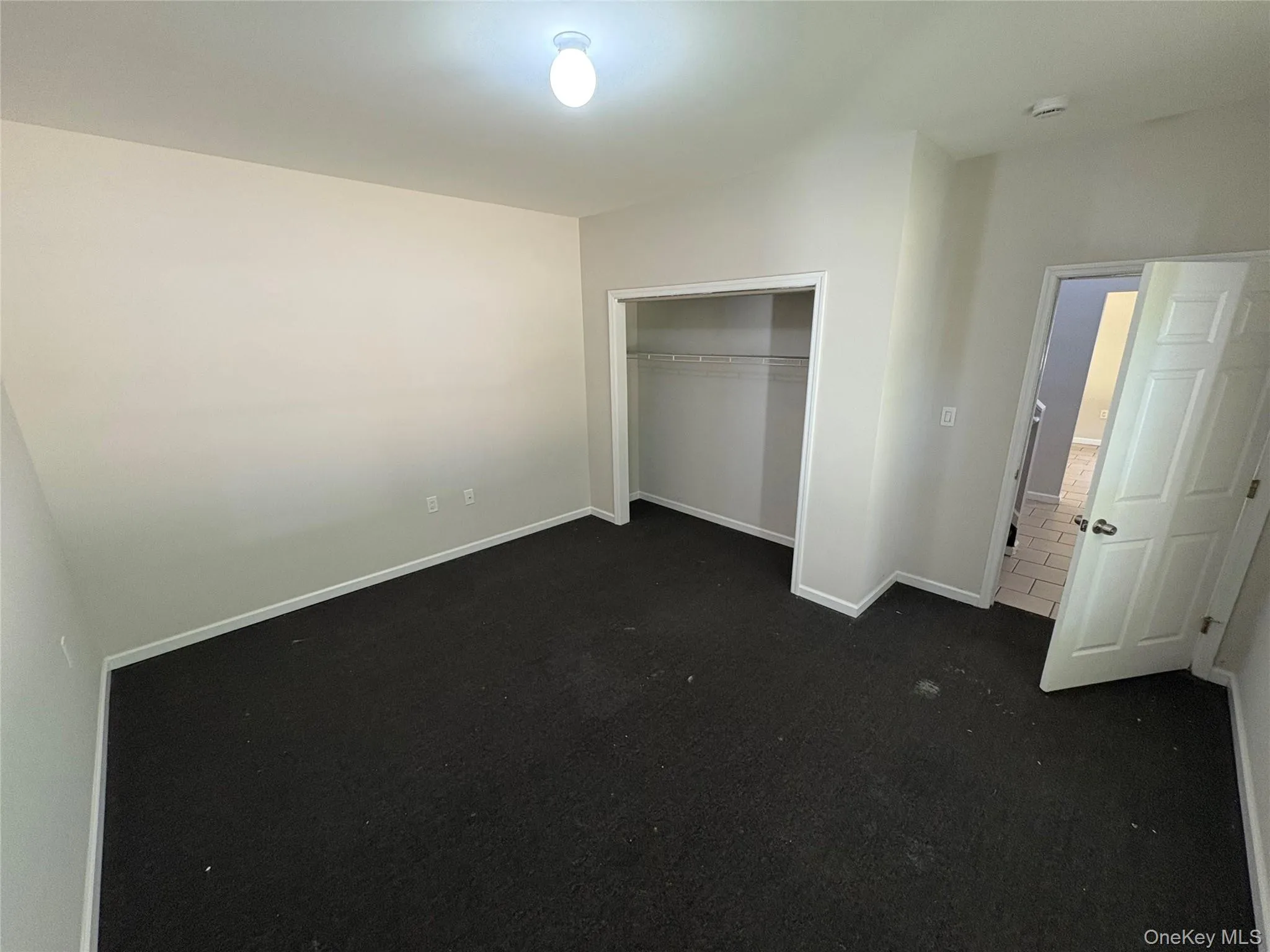 Unfurnished bedroom featuring dark carpet and a closet Unfurnished bedroom featuring dark carpet and a closet