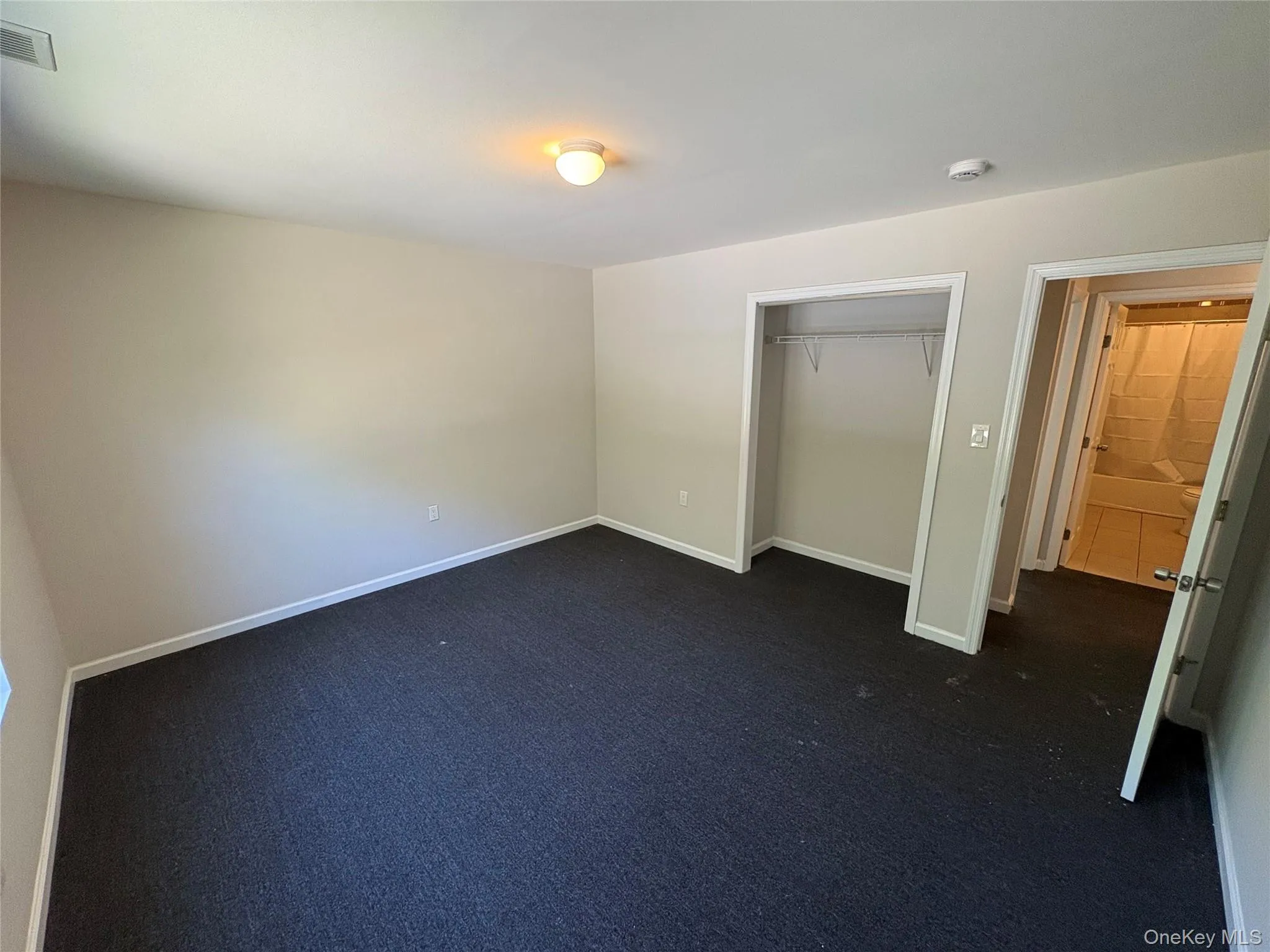 Unfurnished bedroom featuring a closet and dark colored carpet Unfurnished bedroom featuring a closet and dark colored carpet