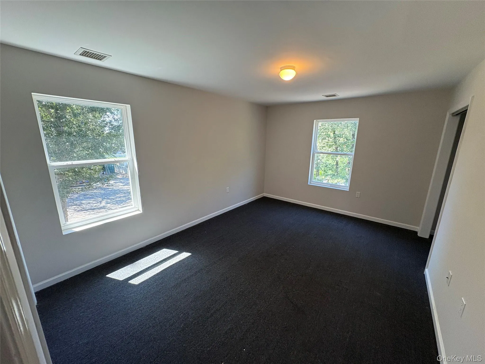 Empty room featuring dark colored carpet and baseboards Empty room featuring dark colored carpet and baseboards
