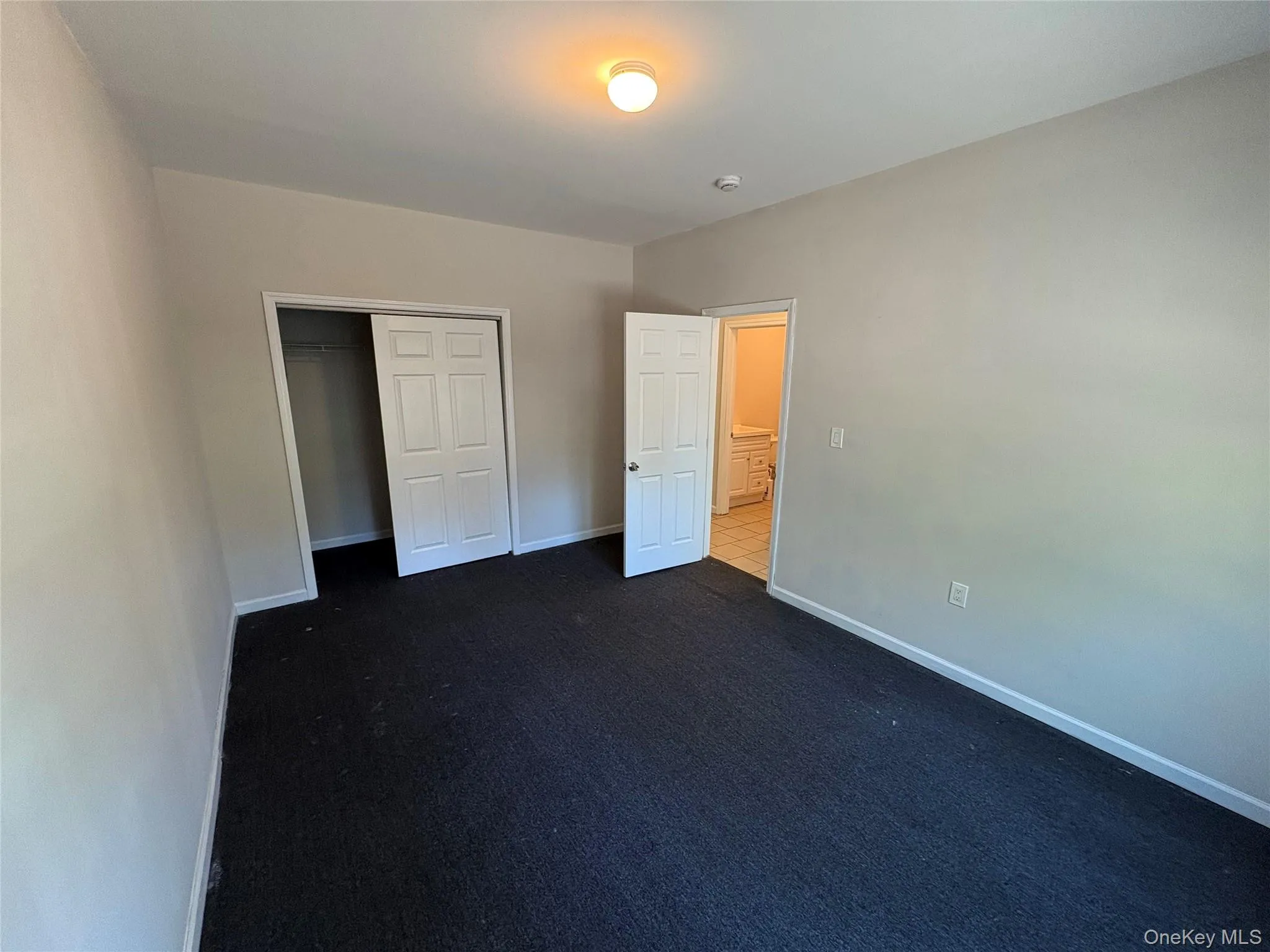 Unfurnished bedroom featuring dark colored carpet and a closet Unfurnished bedroom featuring dark colored carpet and a closet