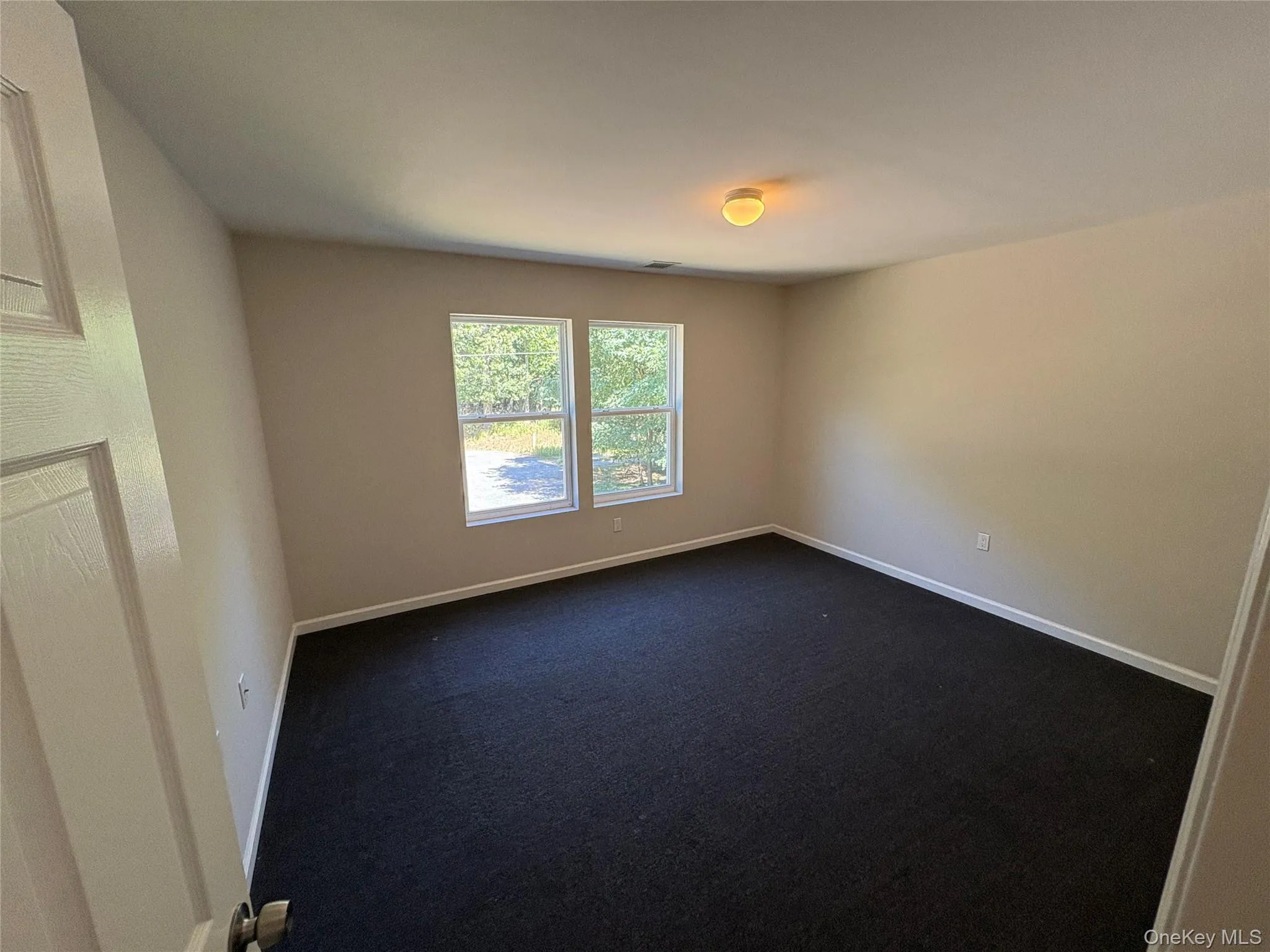 Spare room featuring dark colored carpet and baseboards Spare room featuring dark colored carpet and baseboards