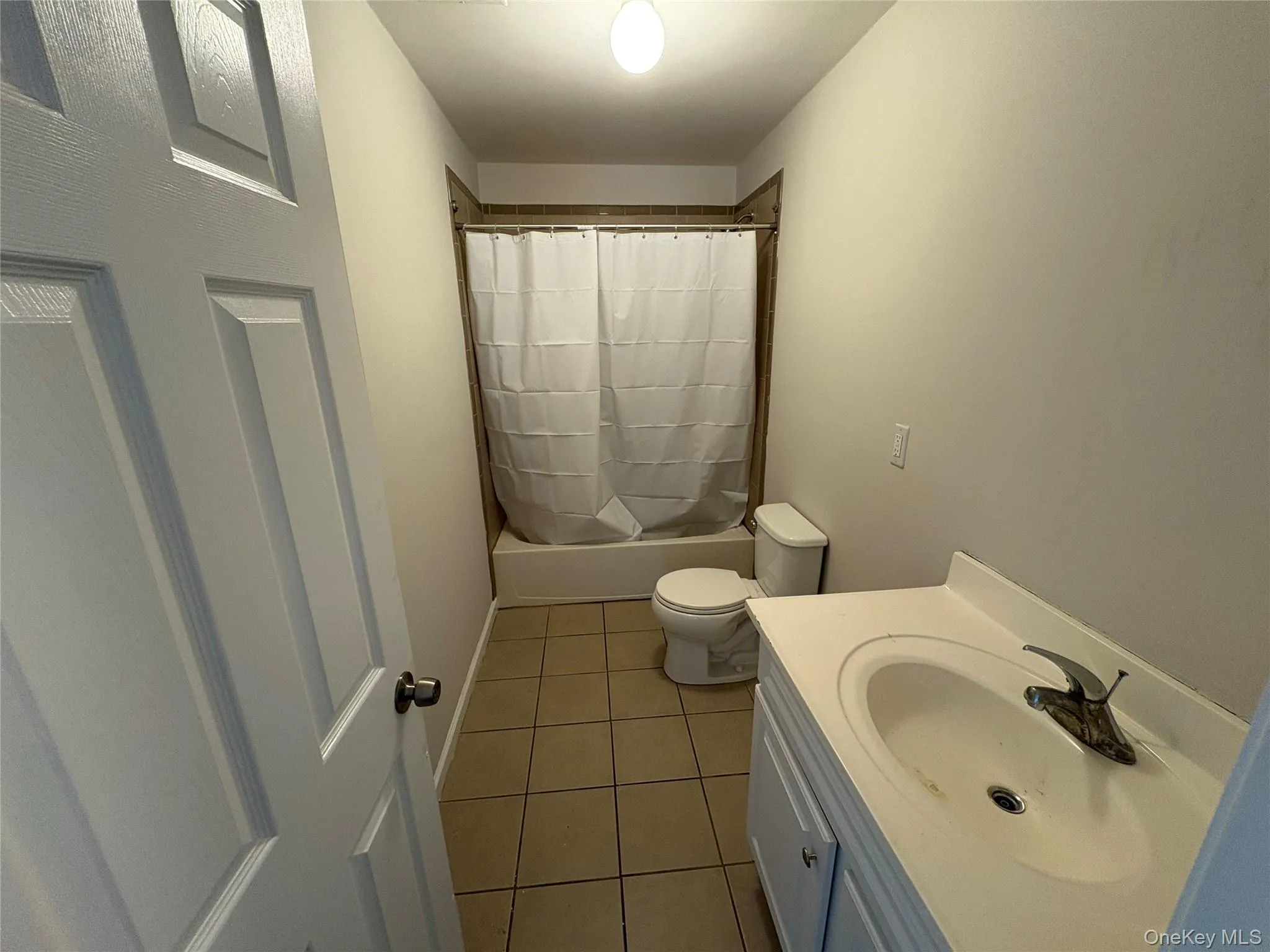 Full bathroom featuring vanity, light tile patterned floors, and shower / bath combo Full bathroom featuring vanity, light tile patterned floors, and shower / bath combo