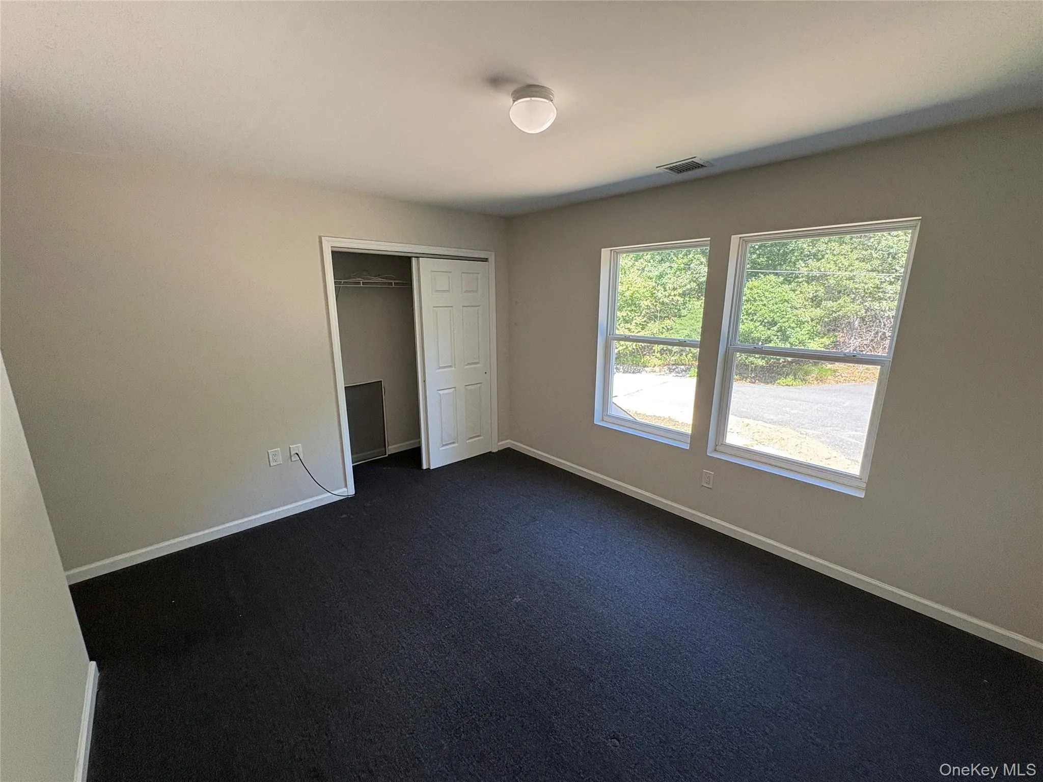 Unfurnished bedroom featuring a closet and dark colored carpet Unfurnished bedroom featuring a closet and dark colored carpet