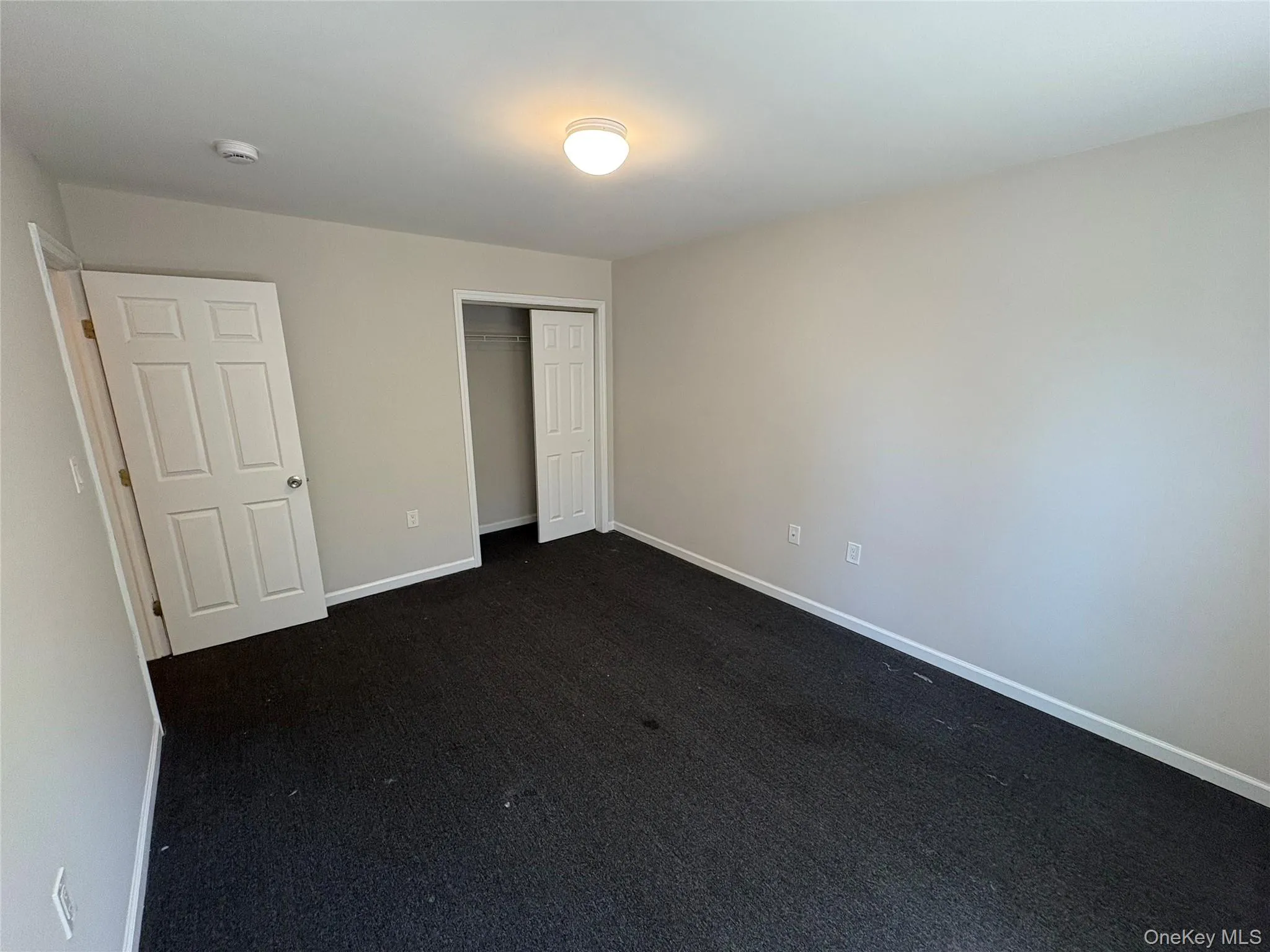 Unfurnished bedroom with a closet and dark carpet Unfurnished bedroom with a closet and dark carpet