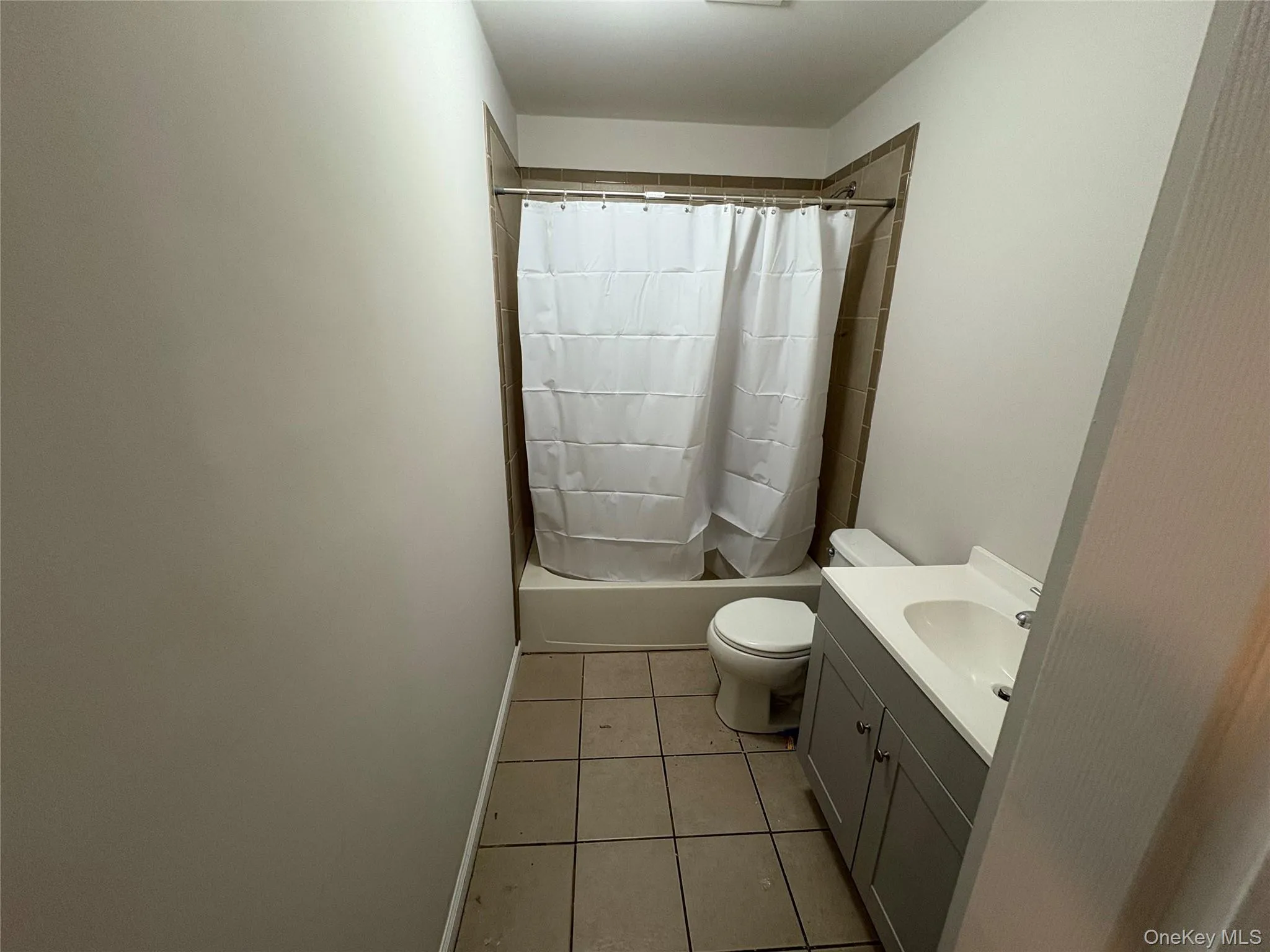 Bathroom with vanity, shower / bath combination with curtain, and light tile patterned flooring Bathroom with vanity, shower / bath combination with curtain, and light tile patterned flooring