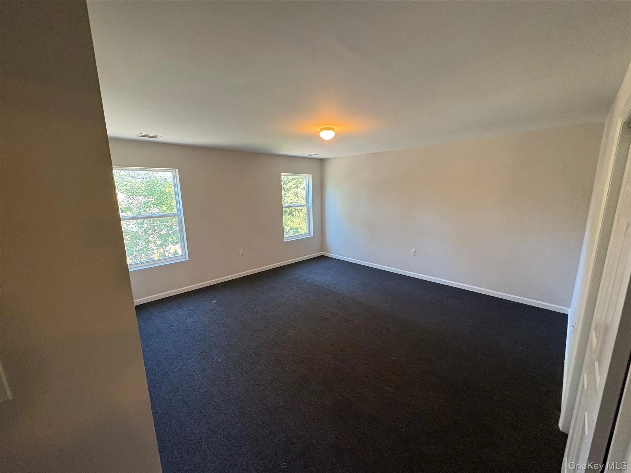 Spare room with dark colored carpet and baseboards Spare room with dark colored carpet and baseboards