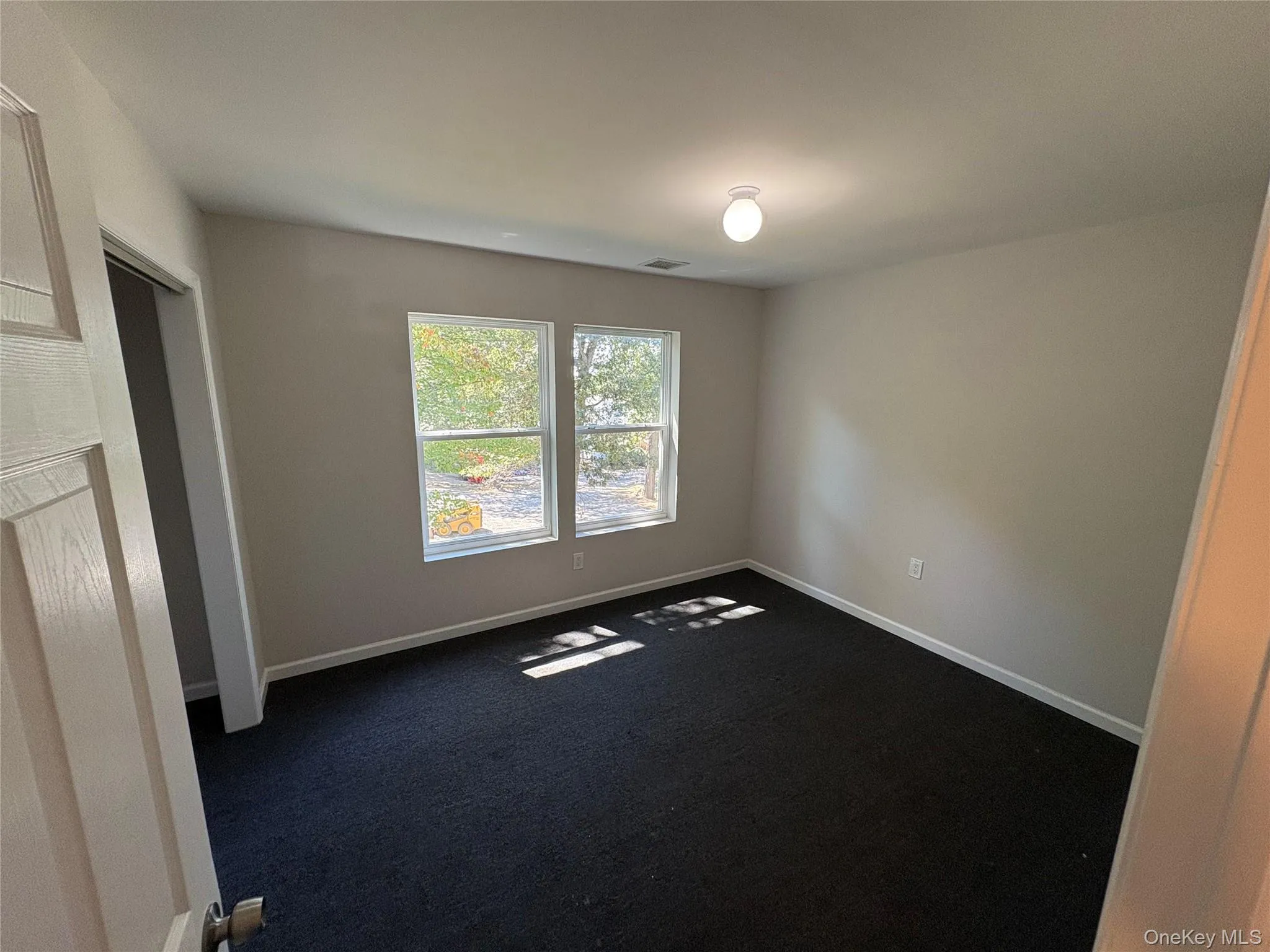 Unfurnished room with dark carpet and baseboards Unfurnished room with dark carpet and baseboards