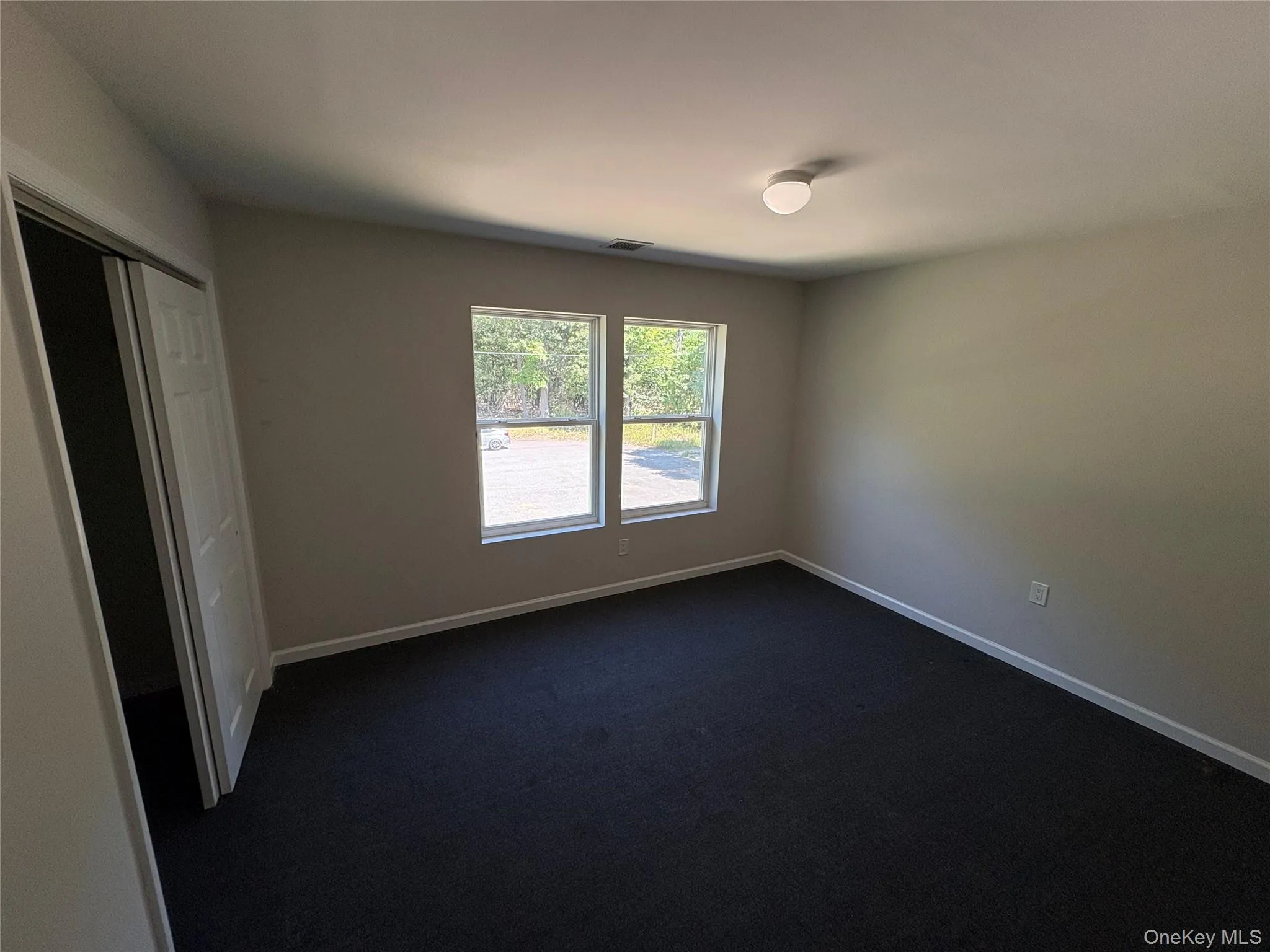 Unfurnished bedroom with a closet and dark colored carpet Unfurnished bedroom with a closet and dark colored carpet