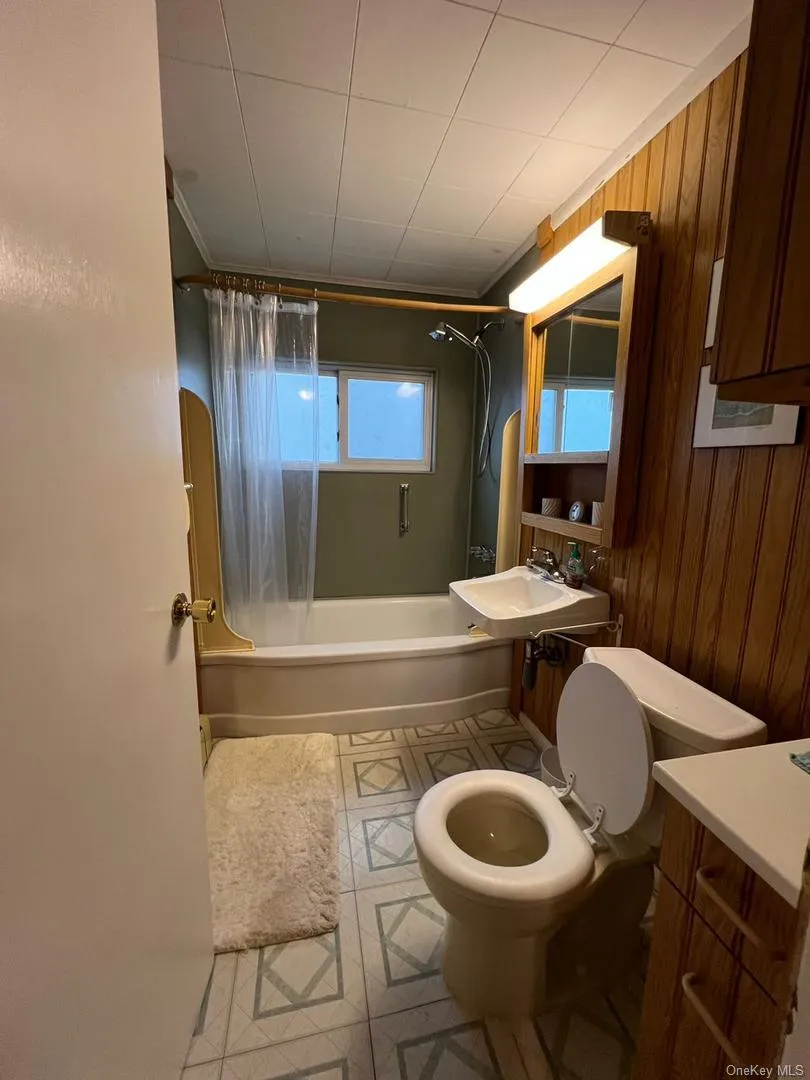 Full bathroom with shower / bathtub combination with curtain and wood walls Full bathroom with shower / bathtub combination with curtain and wood walls