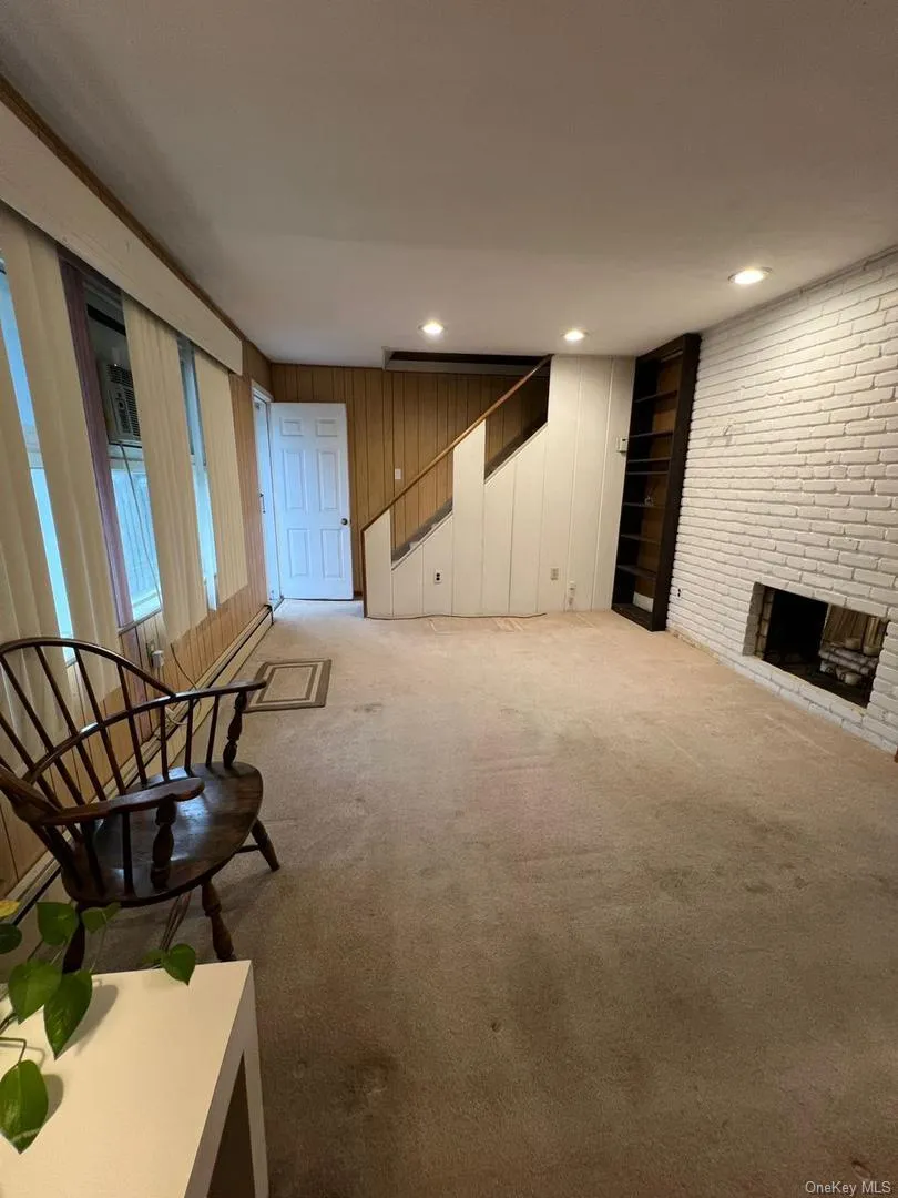 Unfurnished living room with carpet, a fireplace, stairway, and recessed lighting Unfurnished living room with carpet, a fireplace, stairway, and recessed lighting