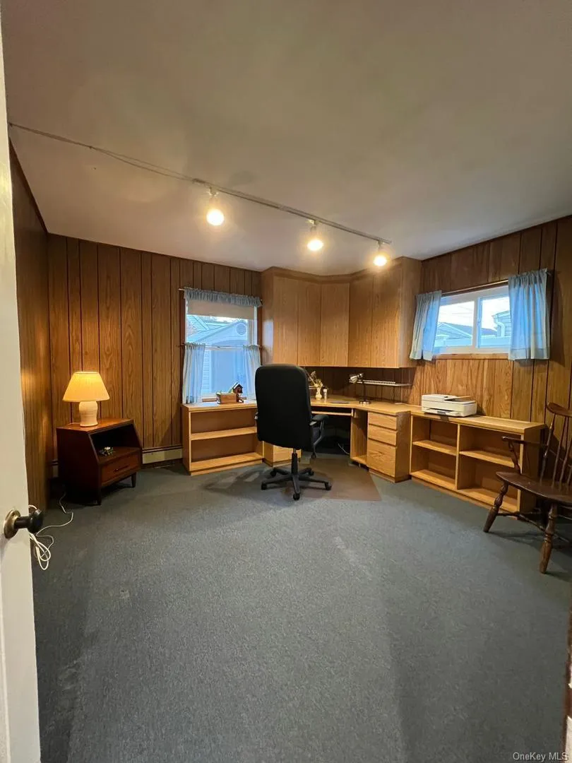 Home office with wood walls, light carpet, and track lighting Home office with wood walls, light carpet, and track lighting