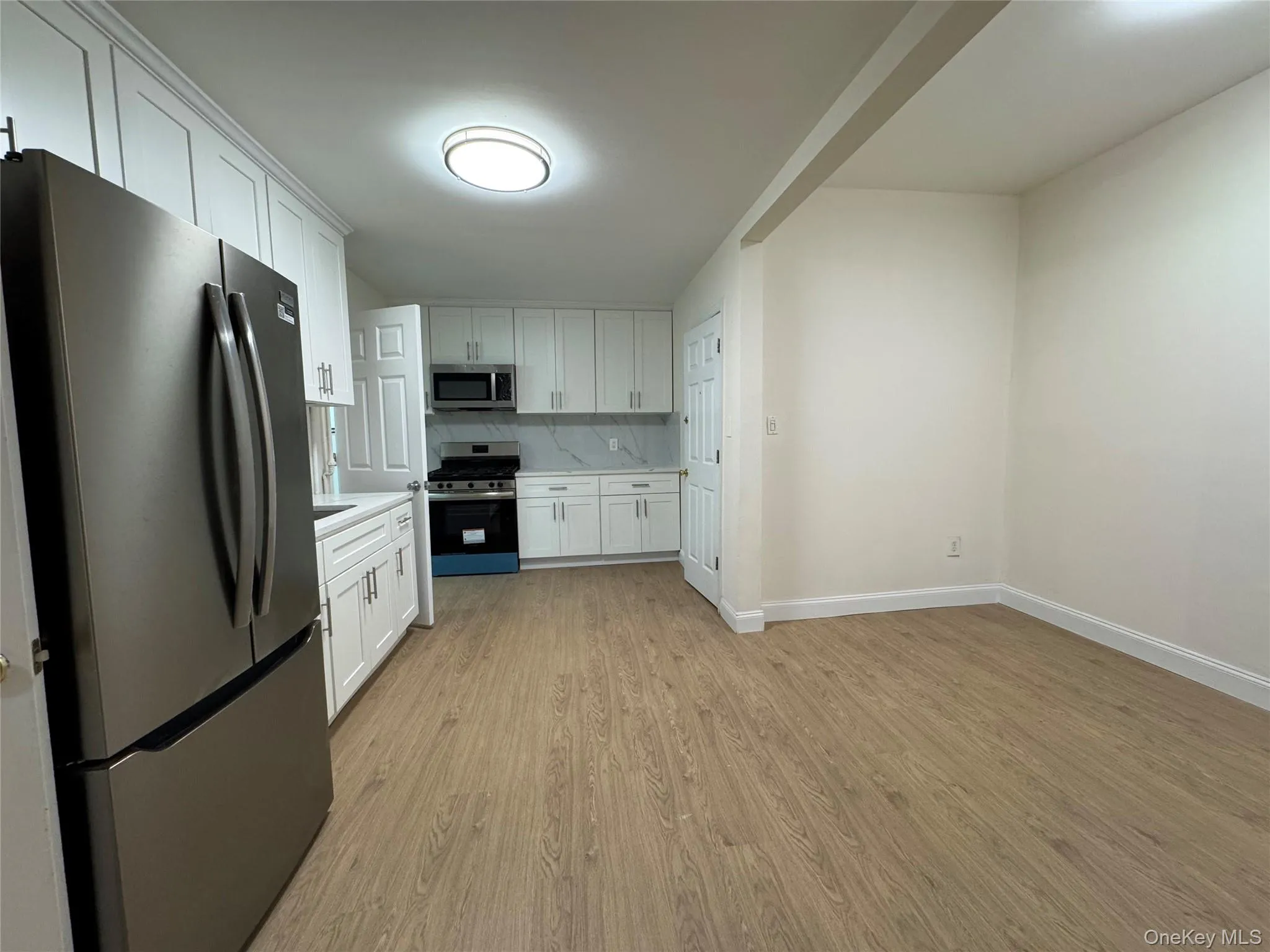 Kitchen featuring appliances with stainless steel finishes, white cabinets, light countertops, and tasteful backsplash Kitchen featuring appliances with stainless steel finishes, white cabinets, light countertops, and tasteful backsplash