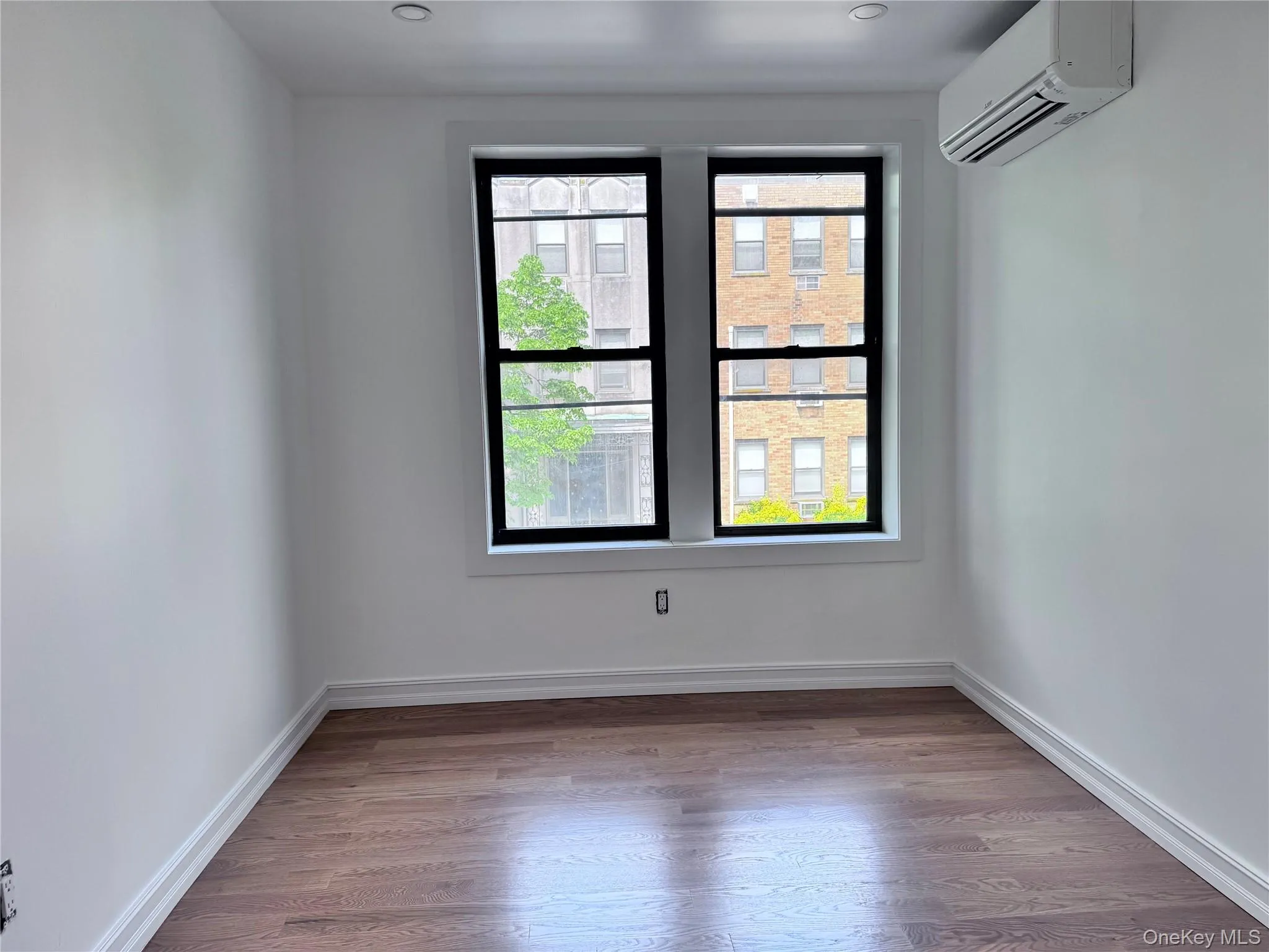 Spare room featuring light wood-type flooring and a wall mounted AC Spare room featuring light wood-type flooring and a wall mounted AC