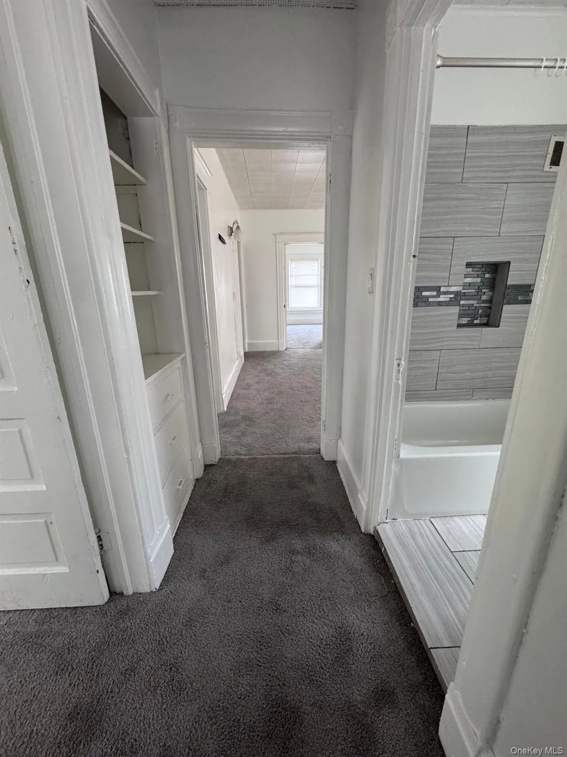 Corridor featuring dark colored carpet and baseboards Corridor featuring dark colored carpet and baseboards