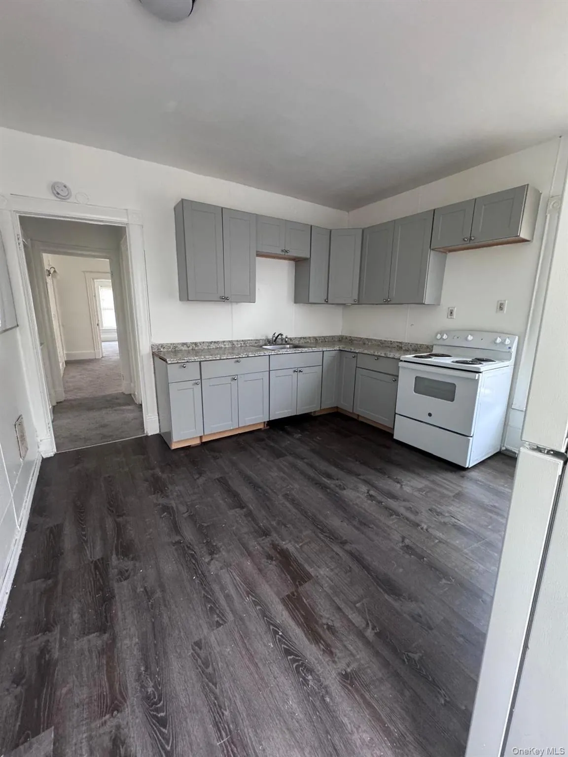 Kitchen featuring gray cabinets, white appliances, and dark wood-type flooring Kitchen featuring gray cabinets, white appliances, and dark wood-type flooring